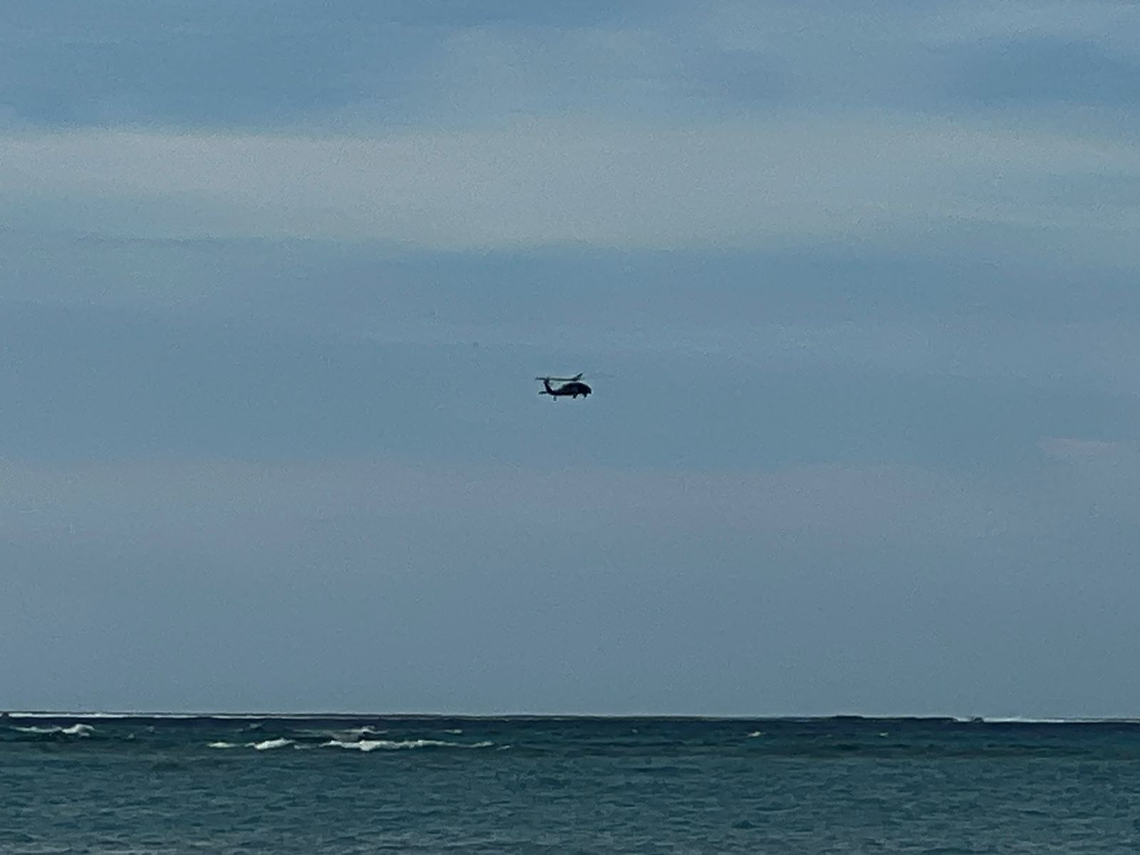 A U.S. Coast Guard helicopter searches for a missing windsurfer in the waters off Micro Beach on Tuesday afternoon.