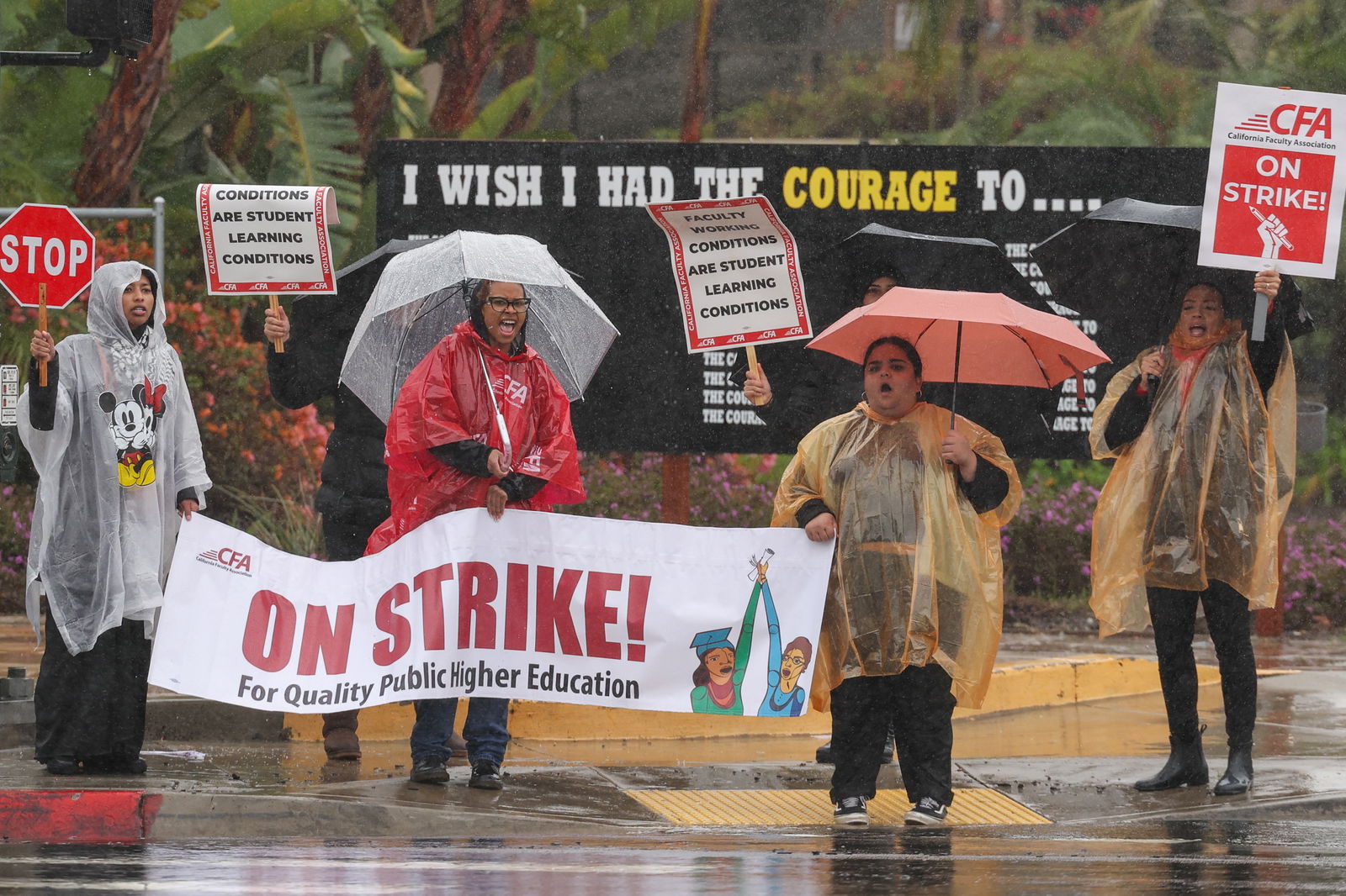 People hold signs and umbrellas while picketing begins at San Diego State University, as the California Faculty Association, the union representing 29,000 professors, lecturers, librarians, counselors and coaches across the California State University, start a planned five-day strike in San Diego, California, U.S. January 22, 2024. 