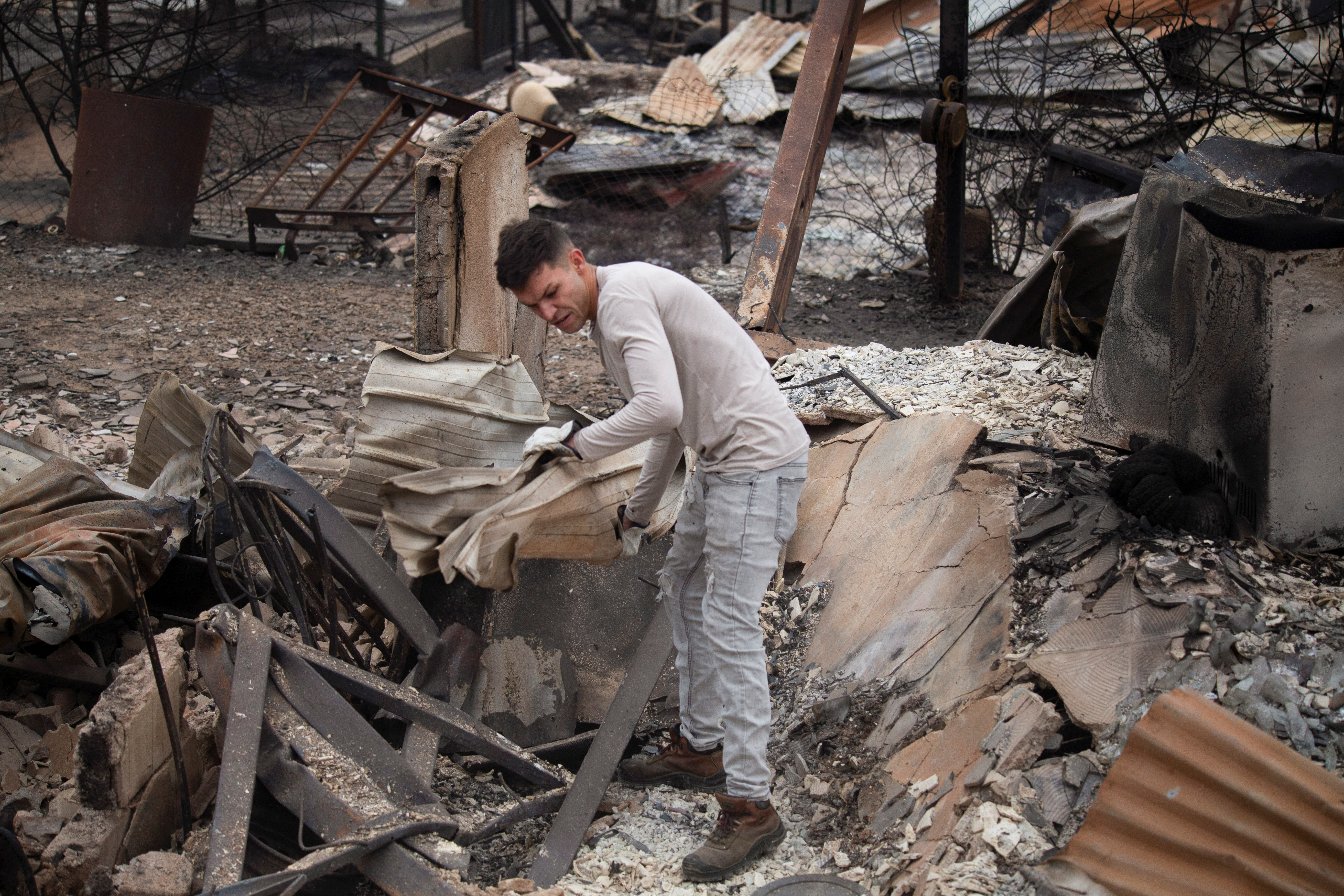 A man clears the remains of burned houses, following the spread of wildfires in Vina del Mar, Chile, February 4, 2024. 