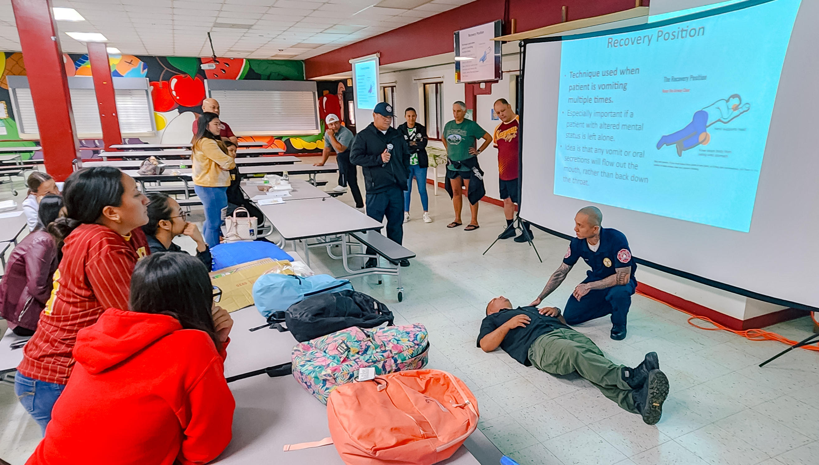 Firefighter Robert Cruz explains the recovery position to training participants at Kagman High School.