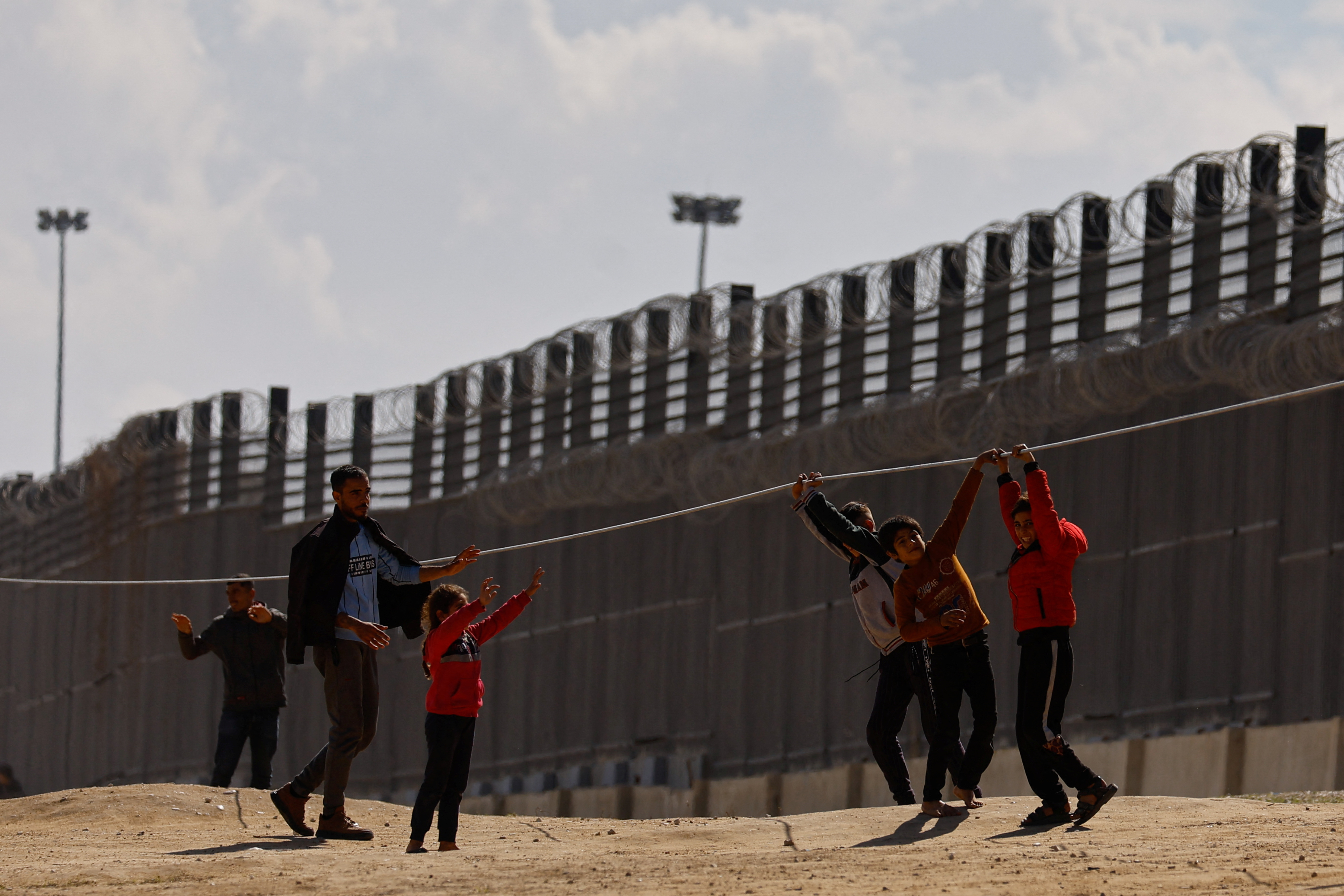 Displaced Palestinian children, who fled their houses due to Israeli strikes, play as they take shelter at the border with Egypt, amid the ongoing conflict between Israel and the Palestinian Islamist group Hamas, in Rafah in the southern Gaza Strip, February 15, 2024. 