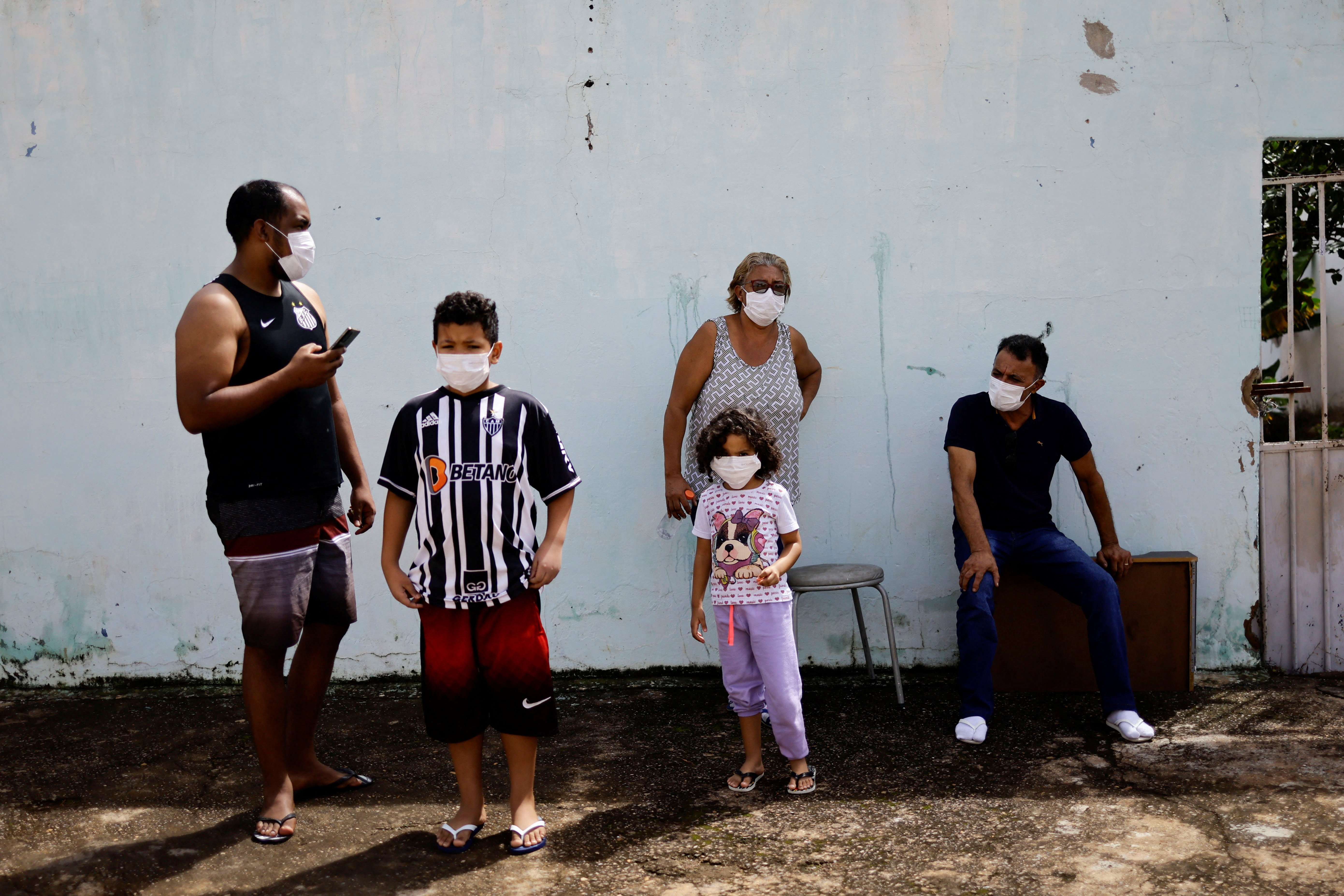 People wear protective masks while watching health workers spraying insecticide to kill the Aedes aegypti mosquito to help mitigate a dengue outbreak, in the Ceilandia neighborhood of Brasilia, Brazil February 7, 2024. 