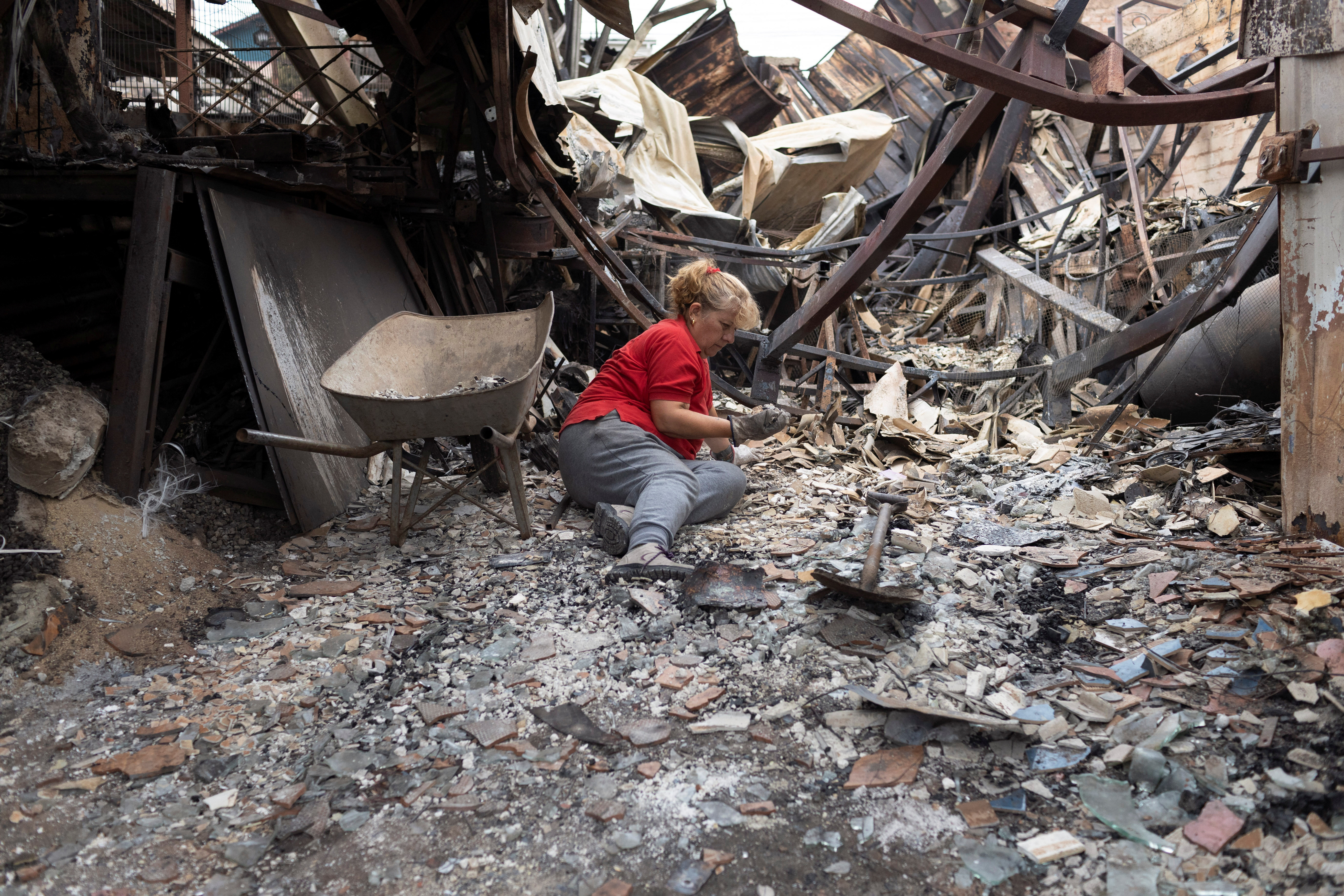 A woman lies among the remains of her burned house, following the spread of wildfires in Vina del Mar, Chile, February 4, 2024. 