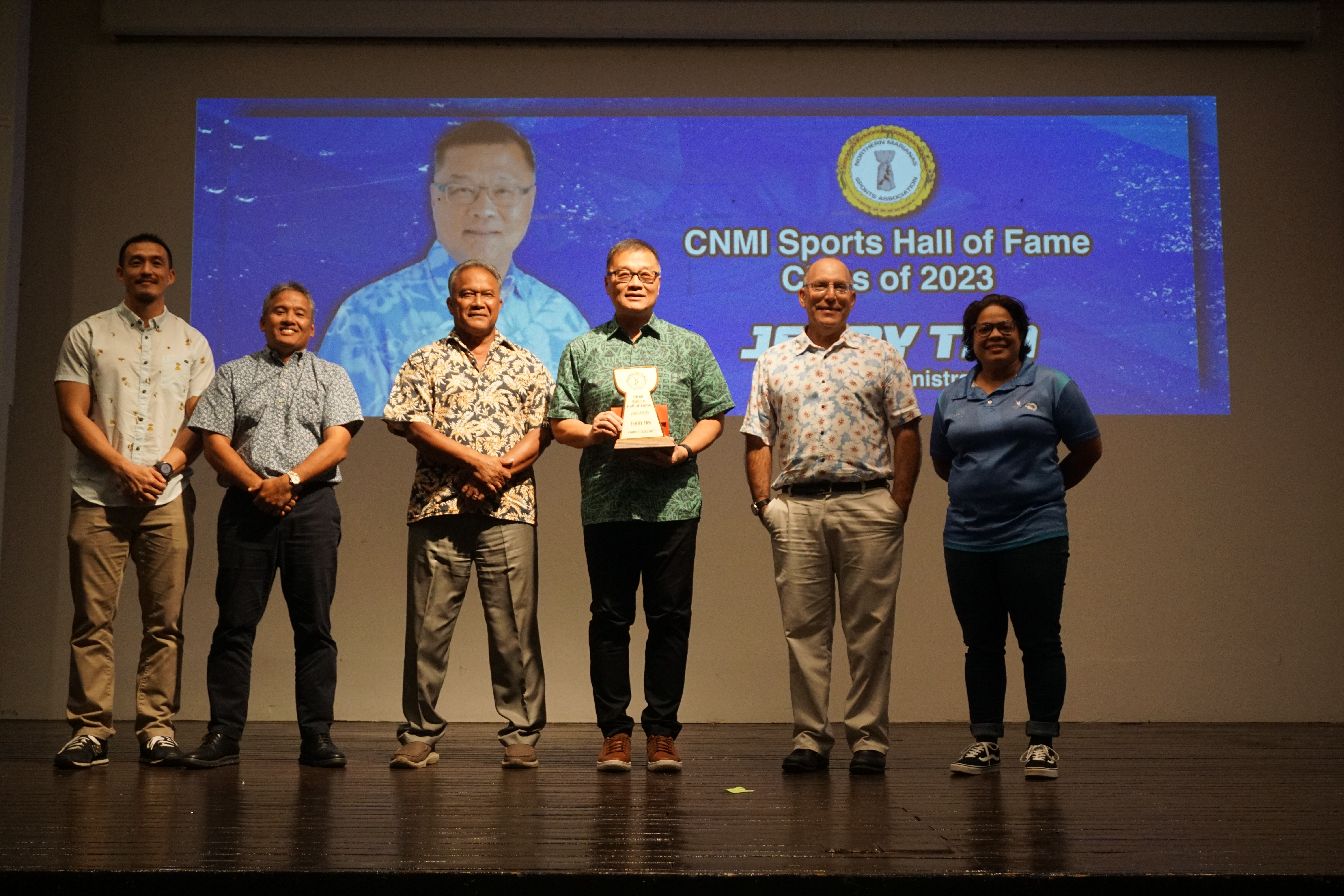 Jerry Tan holds the CNMI Sports Hall of Fame trophy as he poses for a photo with Northern Marianas Sports Association board members during the NMSA Annual Awards Banquet at the Hibiscus Hall of the Crowne Plaza Resort Saipan on Wednesday evening.