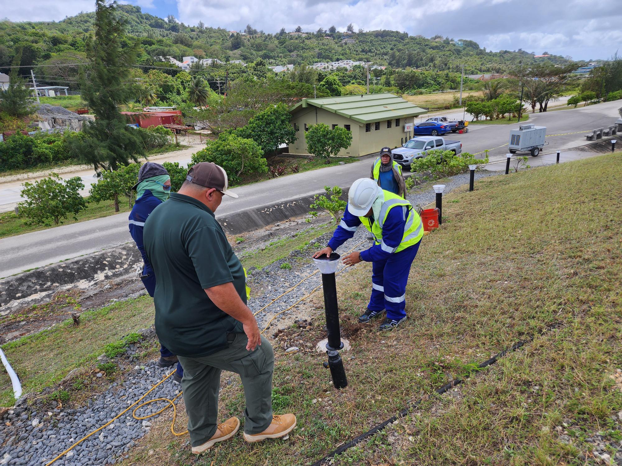 Parks and Rec Director Michael Cruz speaks to a technician replacing the bollard lights at the walkway of the Gov. Eloy S. Inos Peace Park.