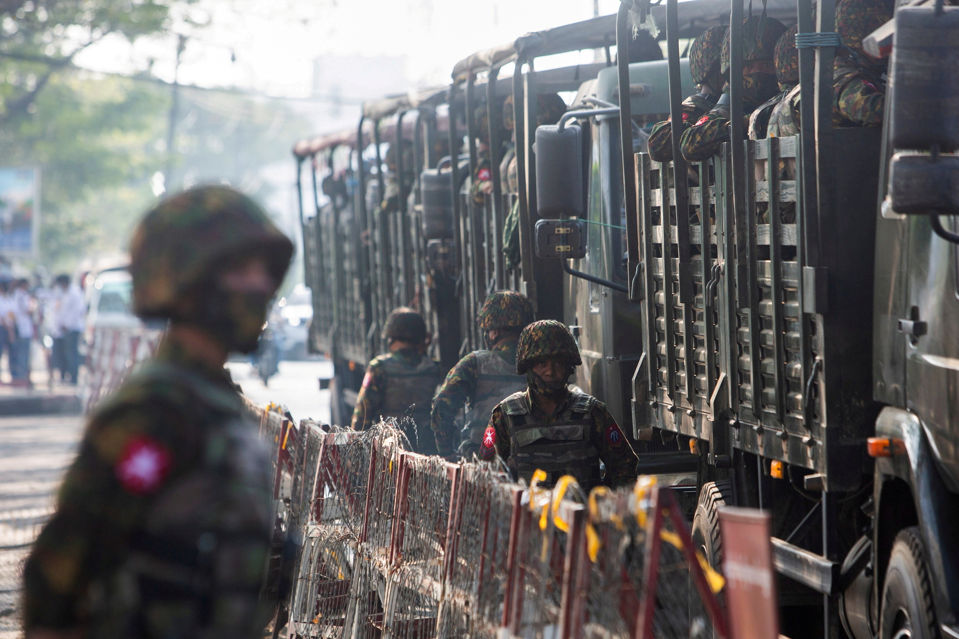 Soldiers stand next to military vehicles as people gather to protest against the military coup, in Yangon, Myanmar, February 15, 2021. 