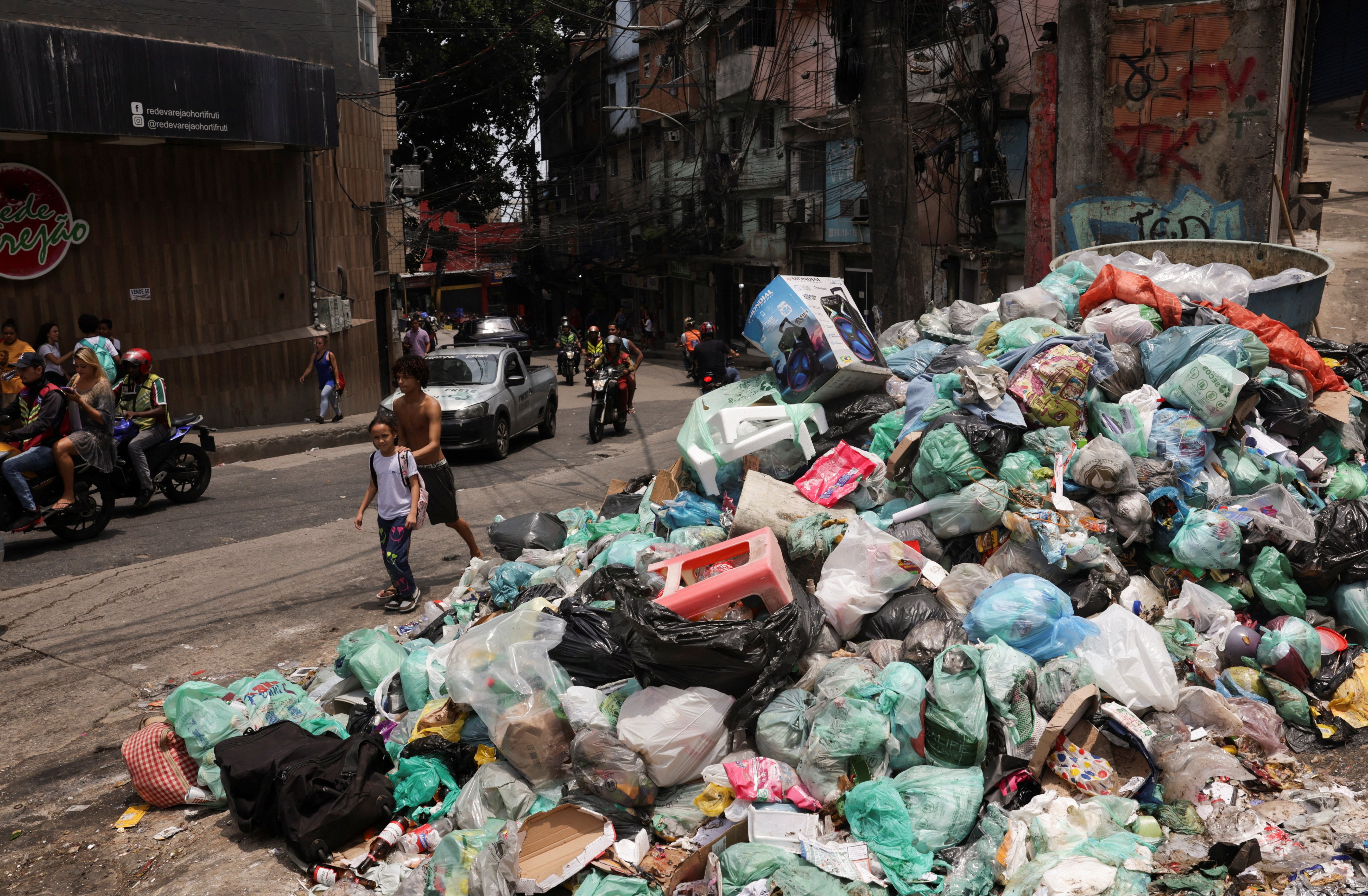 People walk near garbage accumulated on the street in Rocinha slum of Rio de Janeiro, Brazil, February 7, 2024. 