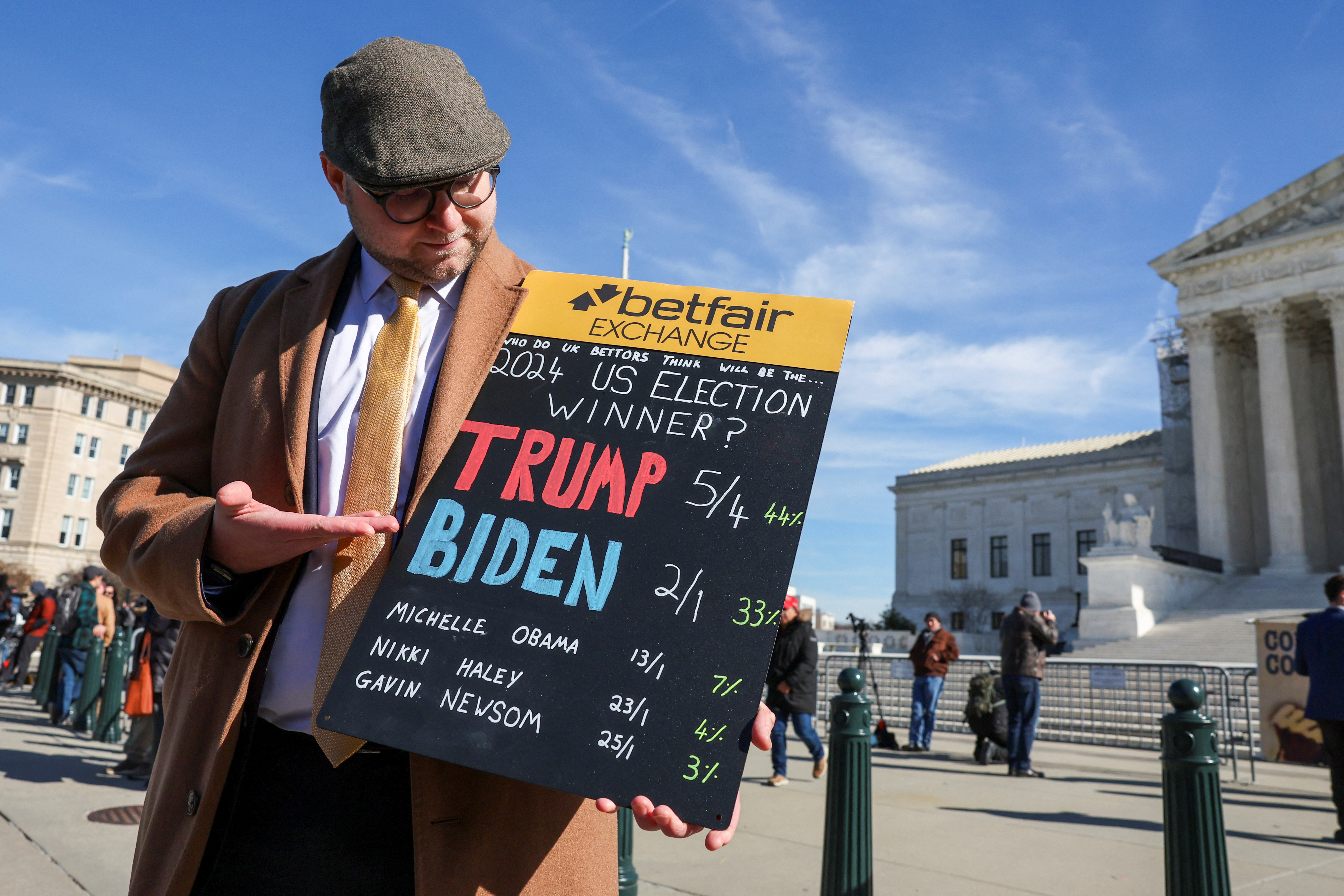 Sam Rosbottom of London, Britain, holds up a sign of election betting odds being tracked by his company, Betfair, outside the U.S. Supreme Court as justices hear arguments in former U.S. President Donald Trump's appeal of a lower court's ruling disqualifying him from the Colorado presidential primary ballot, in Washington, U.S., February 8, 2024. 