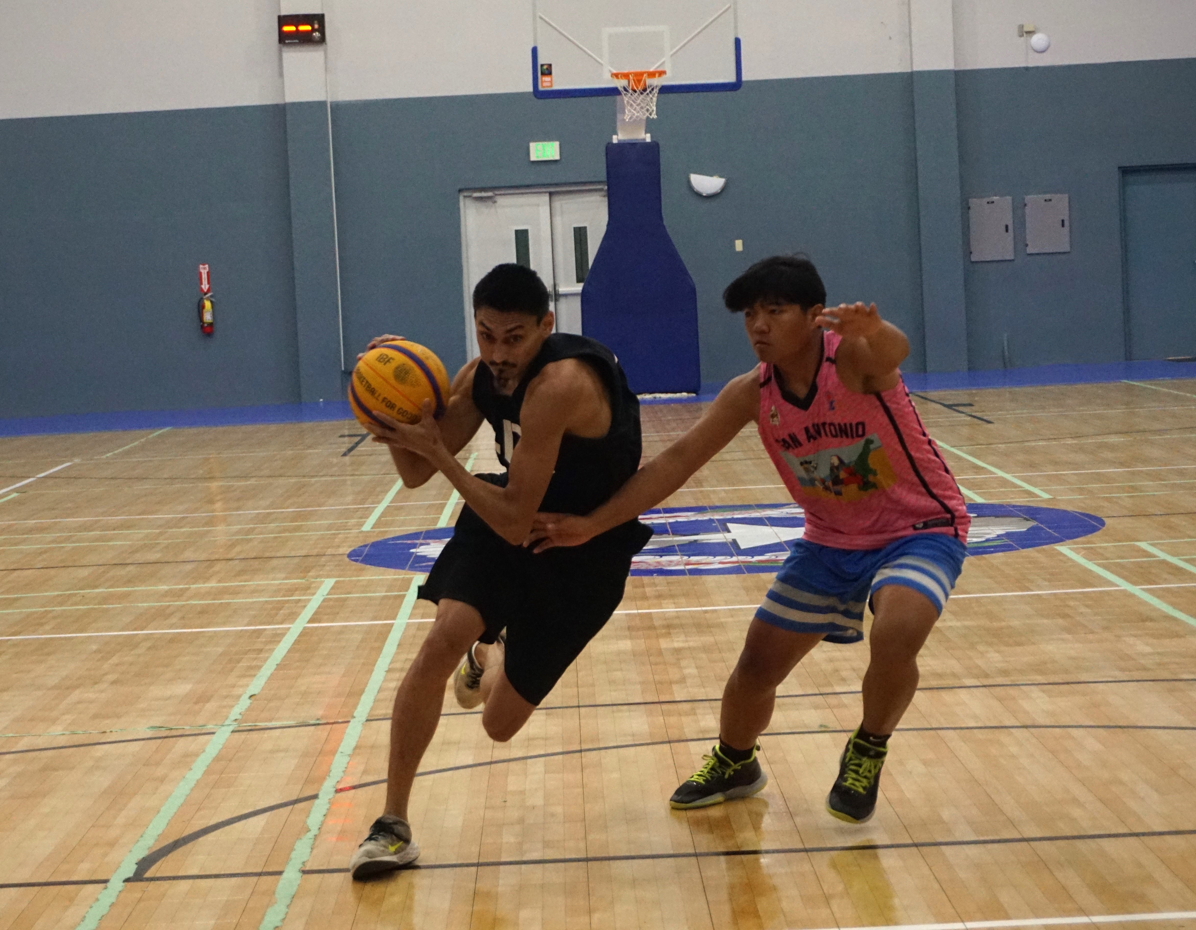 Team Nesian Built's Douglas Schmidt attempts to drive past a defender during an NMIBA Marianas Arsenal 3x3 Basketball Series game at the. Ada gym.