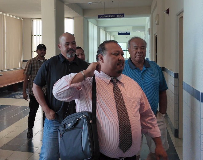 Chief Parole Officer Nick Masga Reyes, 2nd left, enters the courtroom with his attorney, Joaquin DLG Torres, right foreground, on Wednesday.