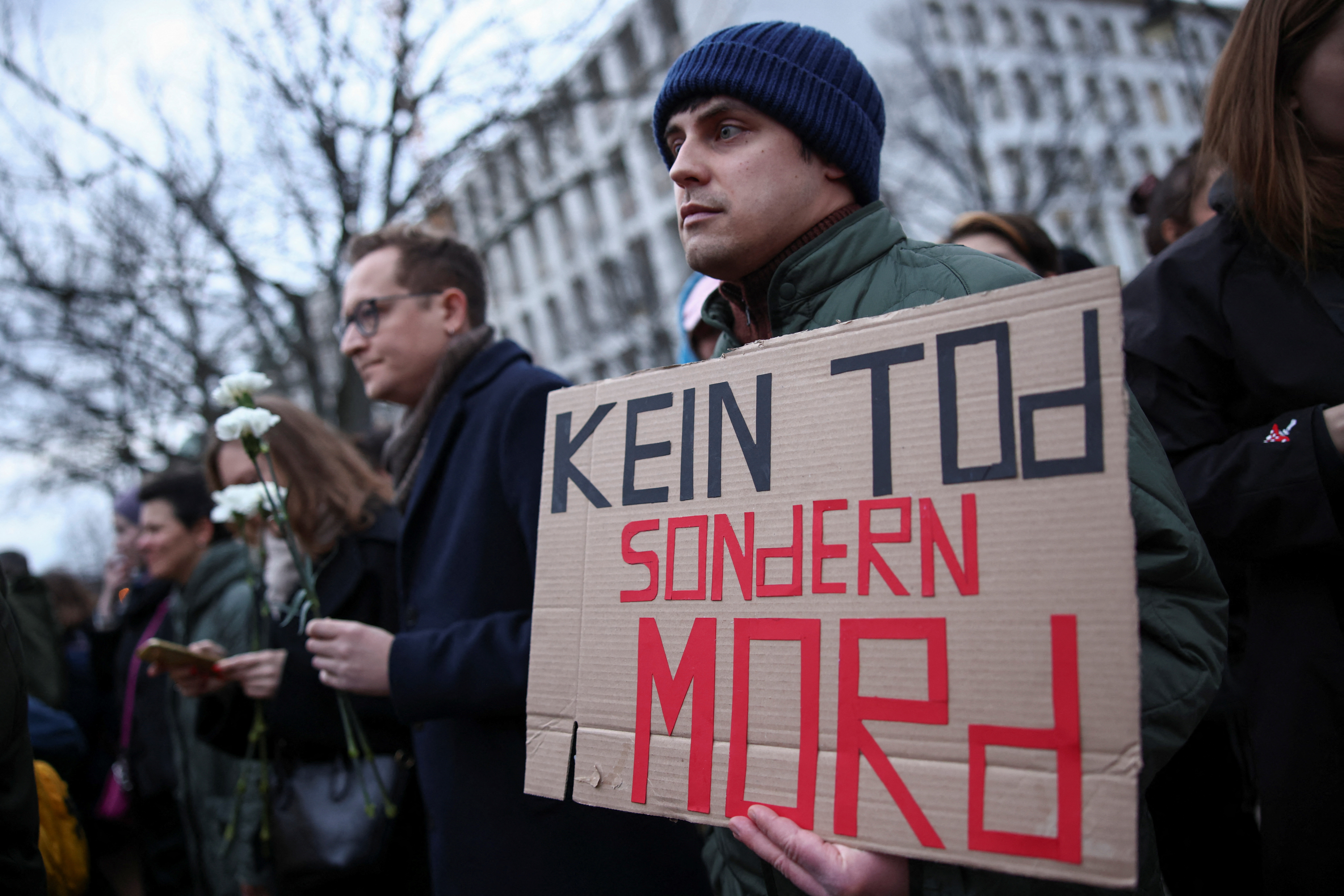 A man holds a placard that reads "Not death, but murder" as he attends a vigil held in front of Russian embassy in Berlin after the death of Russian opposition leader Alexei Navalny, Germany, February 16, 2024. 