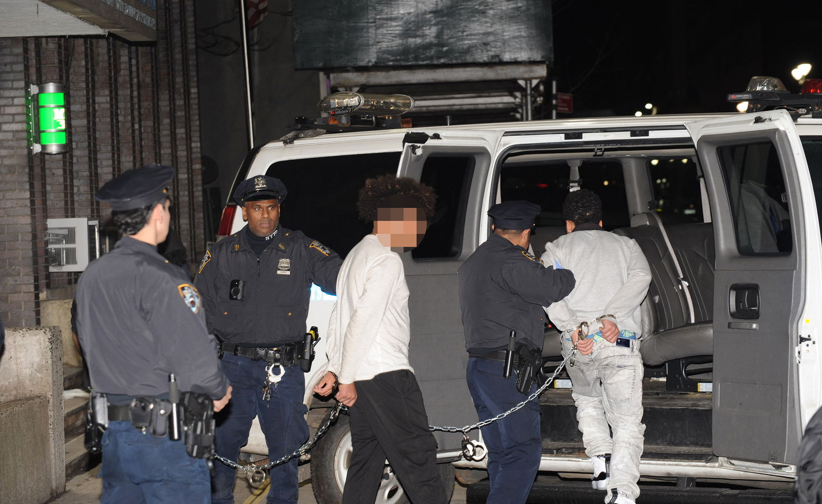 Some of the six people arrested for a bloody brawl that broke out steps from a Times Square migrant shelter are pictured in police custody on Feb. 23, 2024, outside the Midtown South Precinct station house in New York. (Sam Costanza/New York Daily News/TNS)