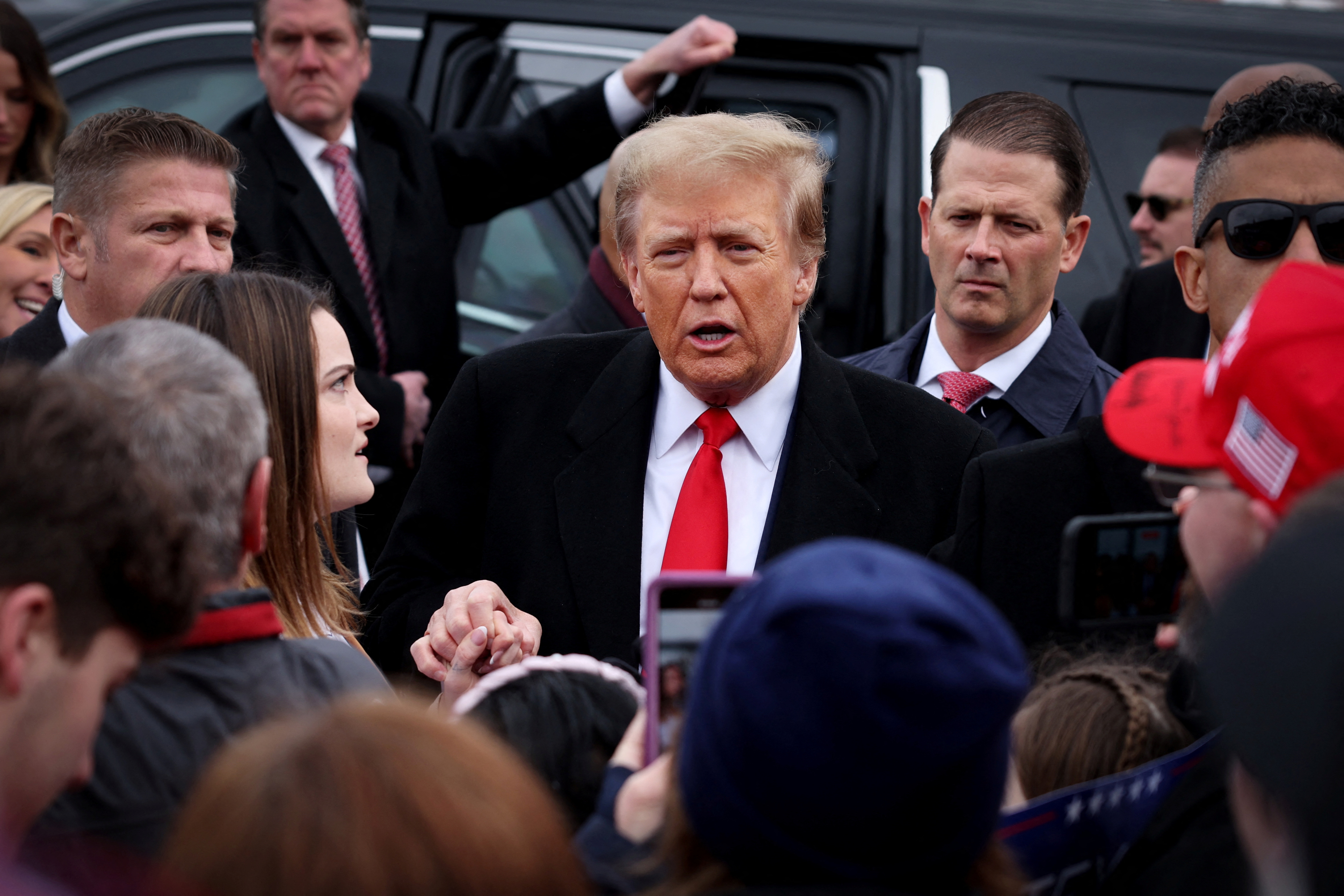 Former U.S. president and Republican presidential candidate Donald Trump greets supporters as he makes a visit to a polling station on election day in the New Hampshire presidential primary in Londonderry, New Hampshire, January 23, 2024. 