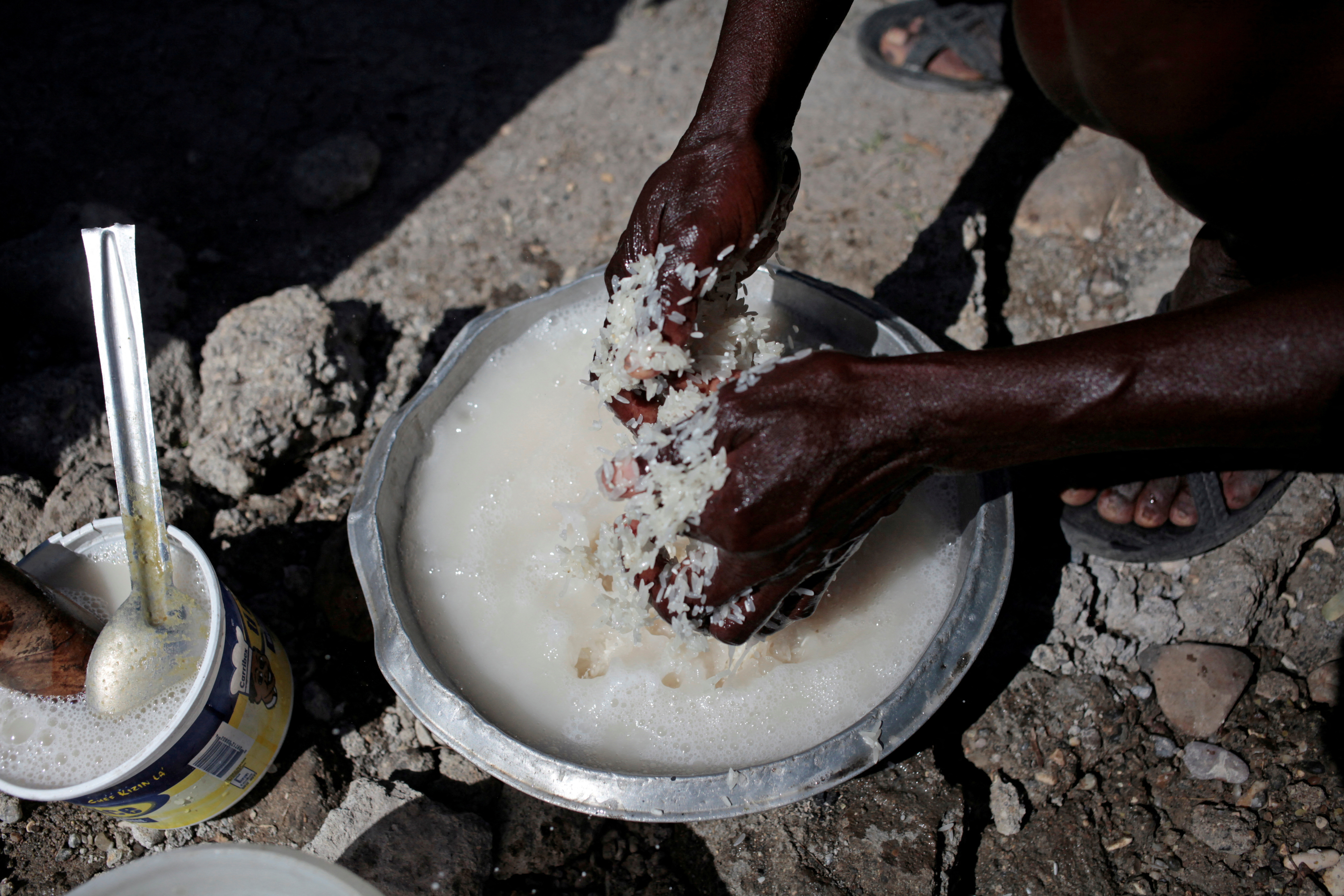FILE PHOTO: A woman washes rice before cooking it next to a house destroyed by Hurricane Matthew in Jeremie, Haiti, November 3, 2016. 