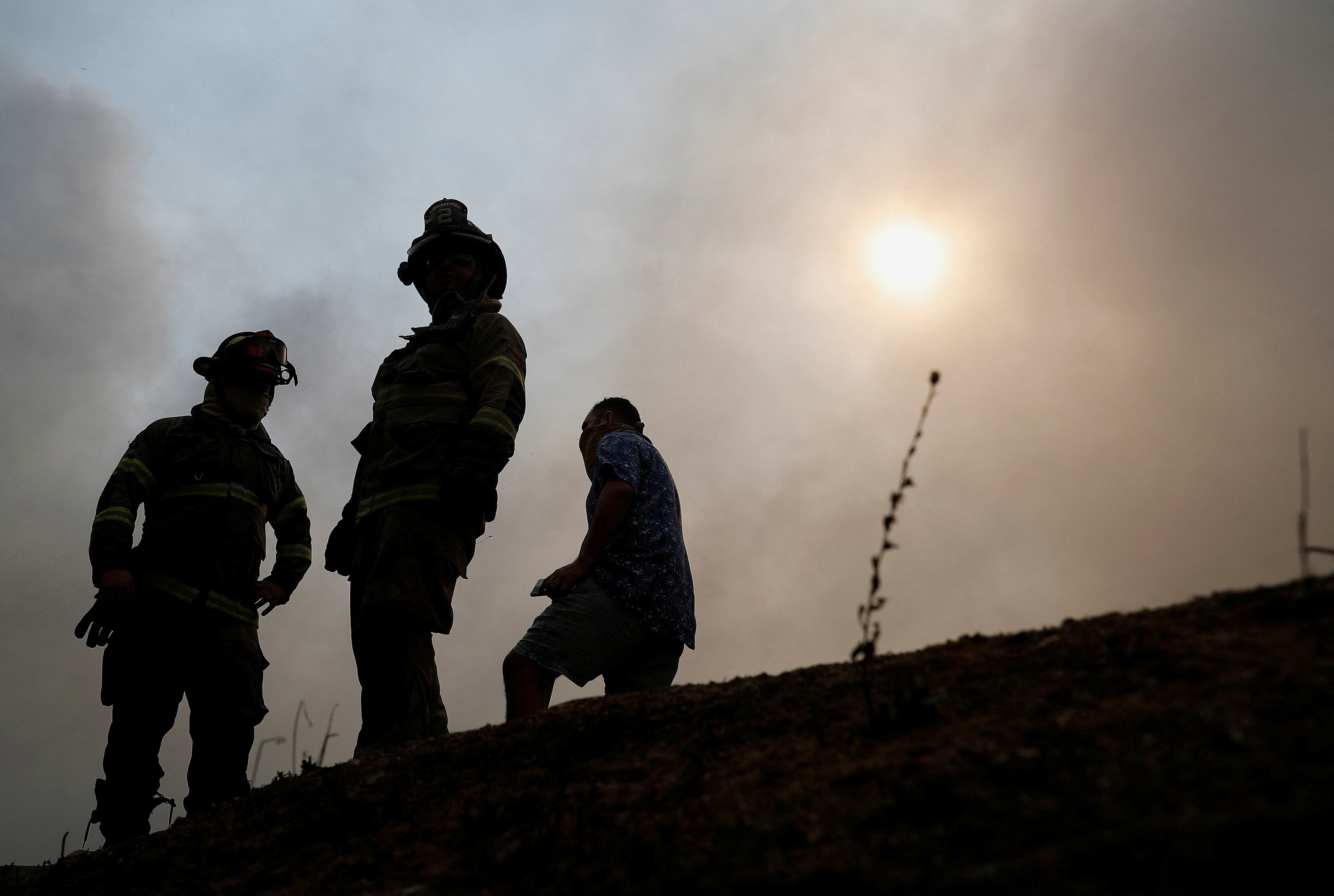 Firefighters stand amid the spread of wildfires in Vina del Mar, Chile February 3, 2024. 