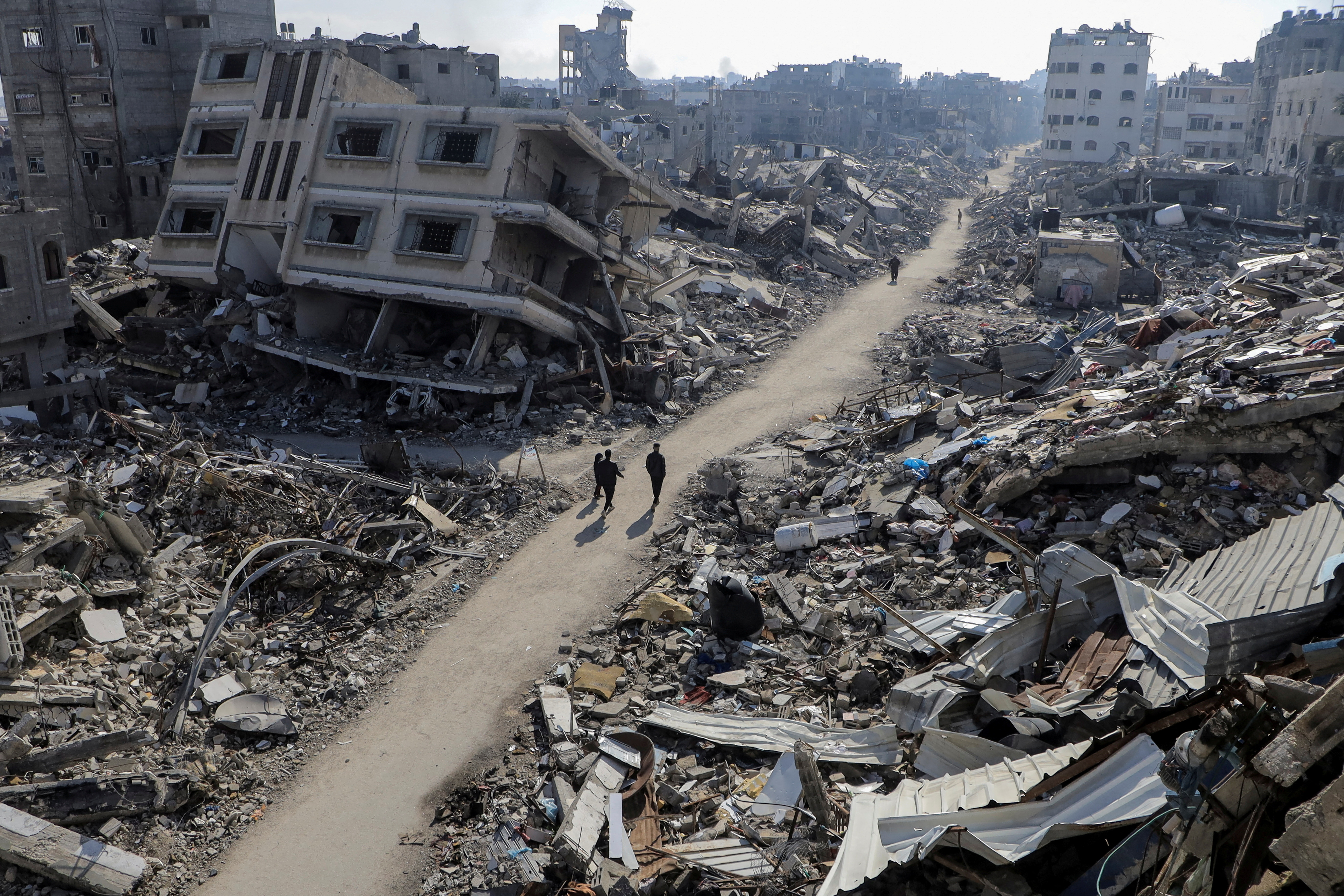 Palestinians walk past destroyed houses, amid the ongoing conflict between Israel and Hamas, in Jabalia refugee camp, in the northern Gaza Strip February 22, 2024. 