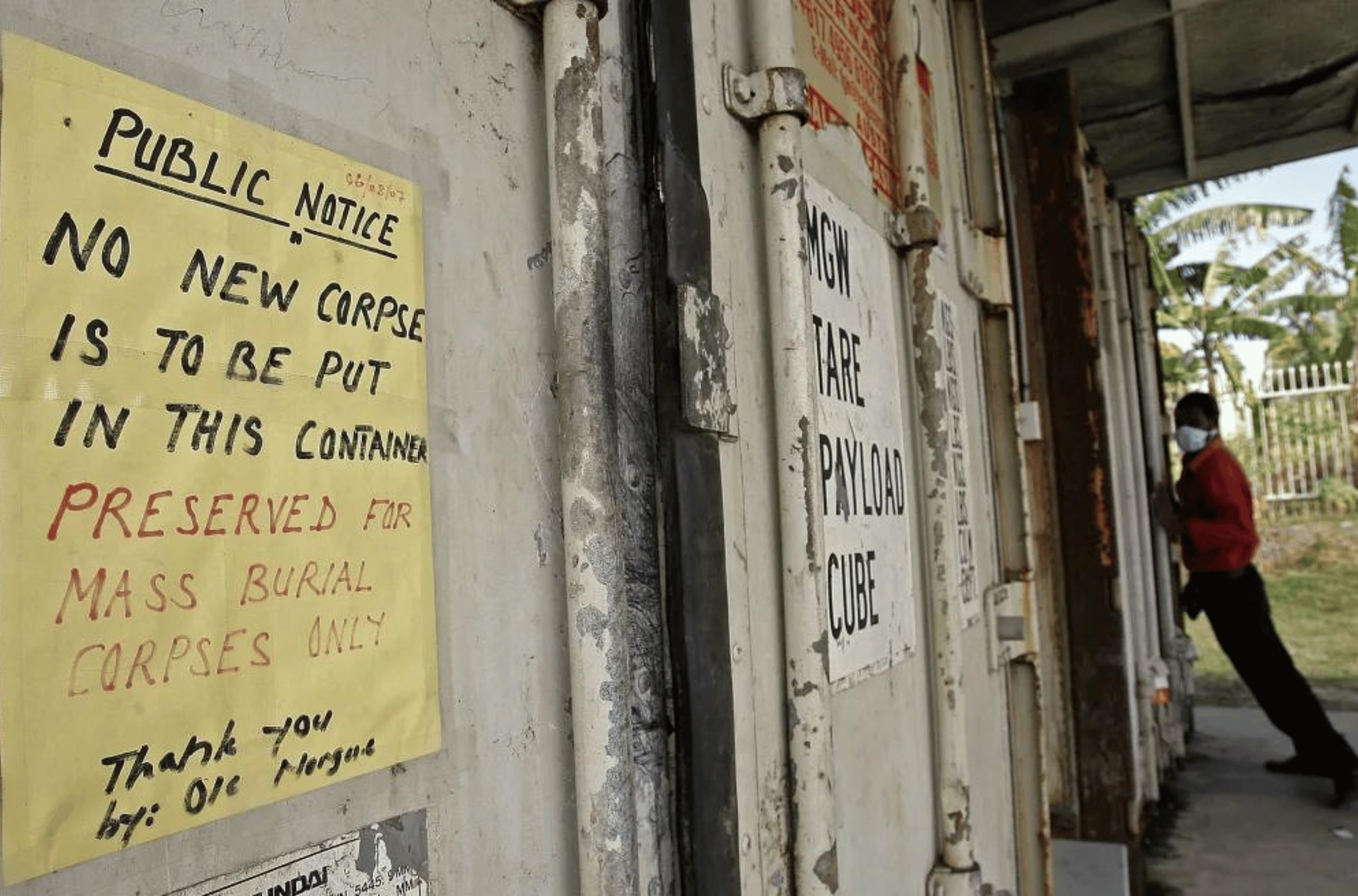 Morgue attendant Gideon Mati (R) struggles to close a refrigerated shipping container filled with unclaimed corpses behind Port Moresby General hospital, 2007. 