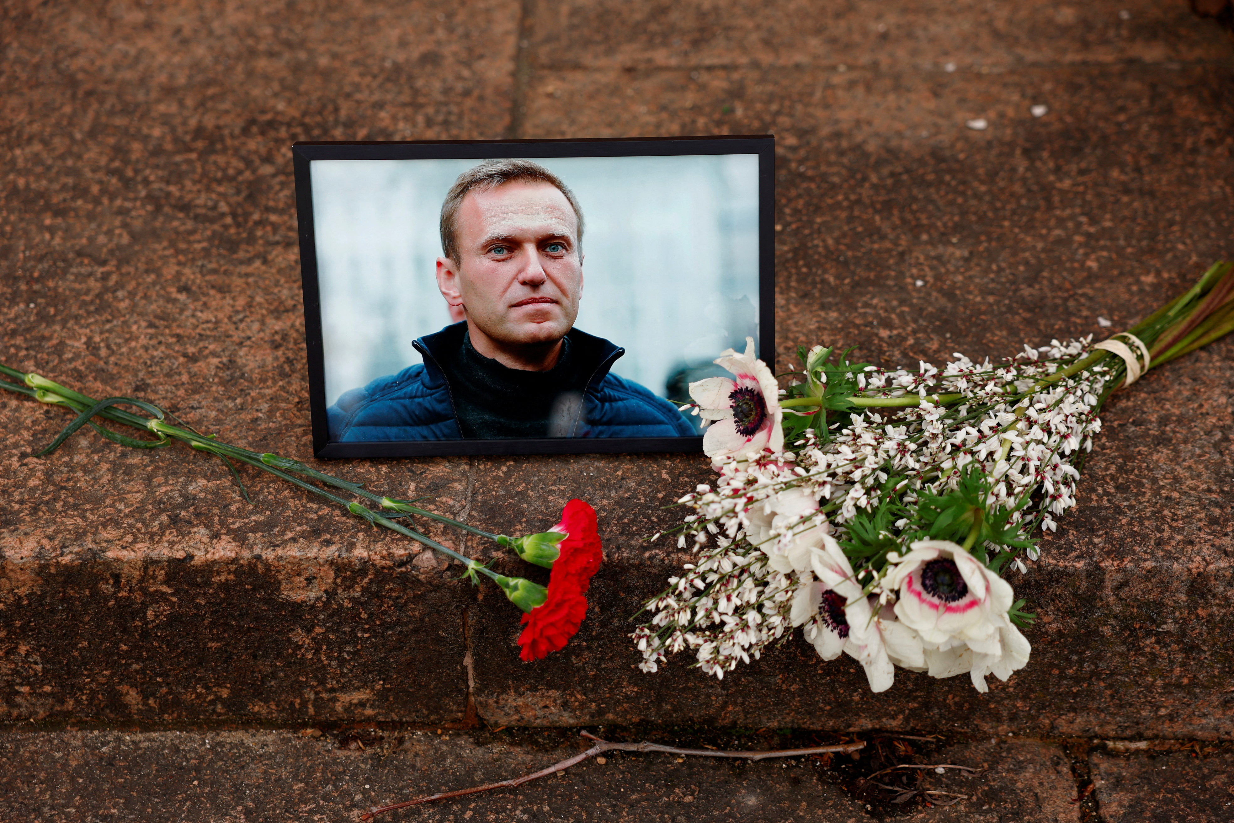 Flowers and a portrait of Russian opposition leader Alexei Navalny are seen following Navalny's death, as people gather near the Russian embassy in Paris, France, February 16, 2024. 