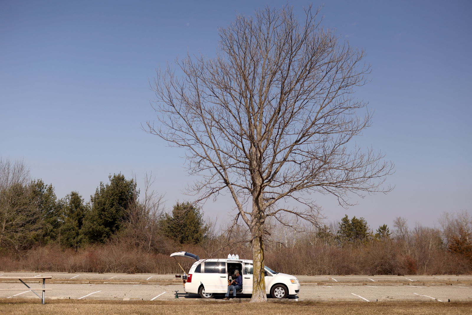 Jim Brown, who lives full time in his van, plays a broken guitar he purchased in a pawnshop while enjoying the sun at Sessions Lake, in Ionia, Michigan, U.S. February 27, 2024. 