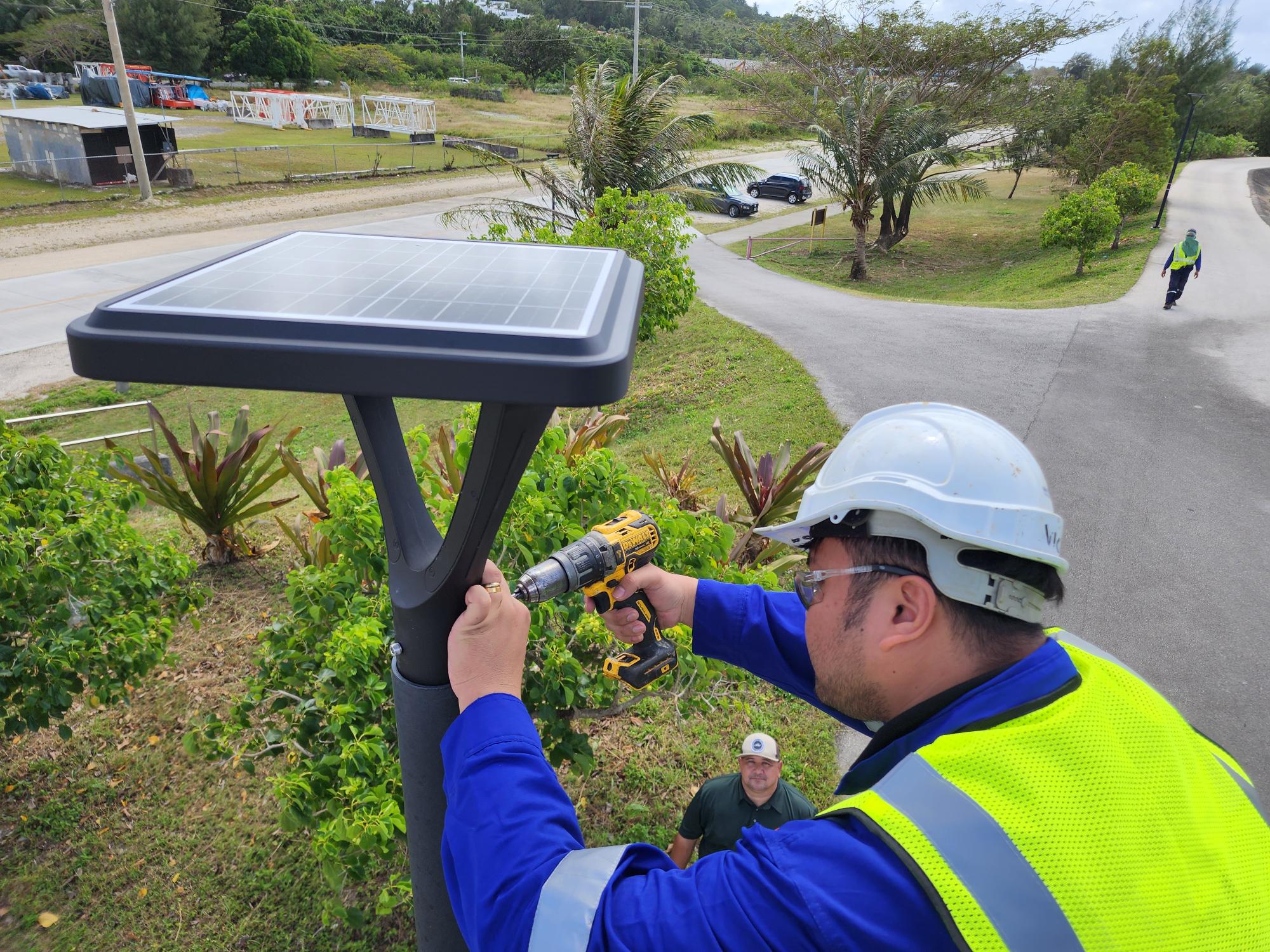 Parks and Rec Director Michael Cruz, background, looks on while a technician replaces one of the solar panels at the Gov. Eloy S. Inos Peace Park on Monday afternoon.