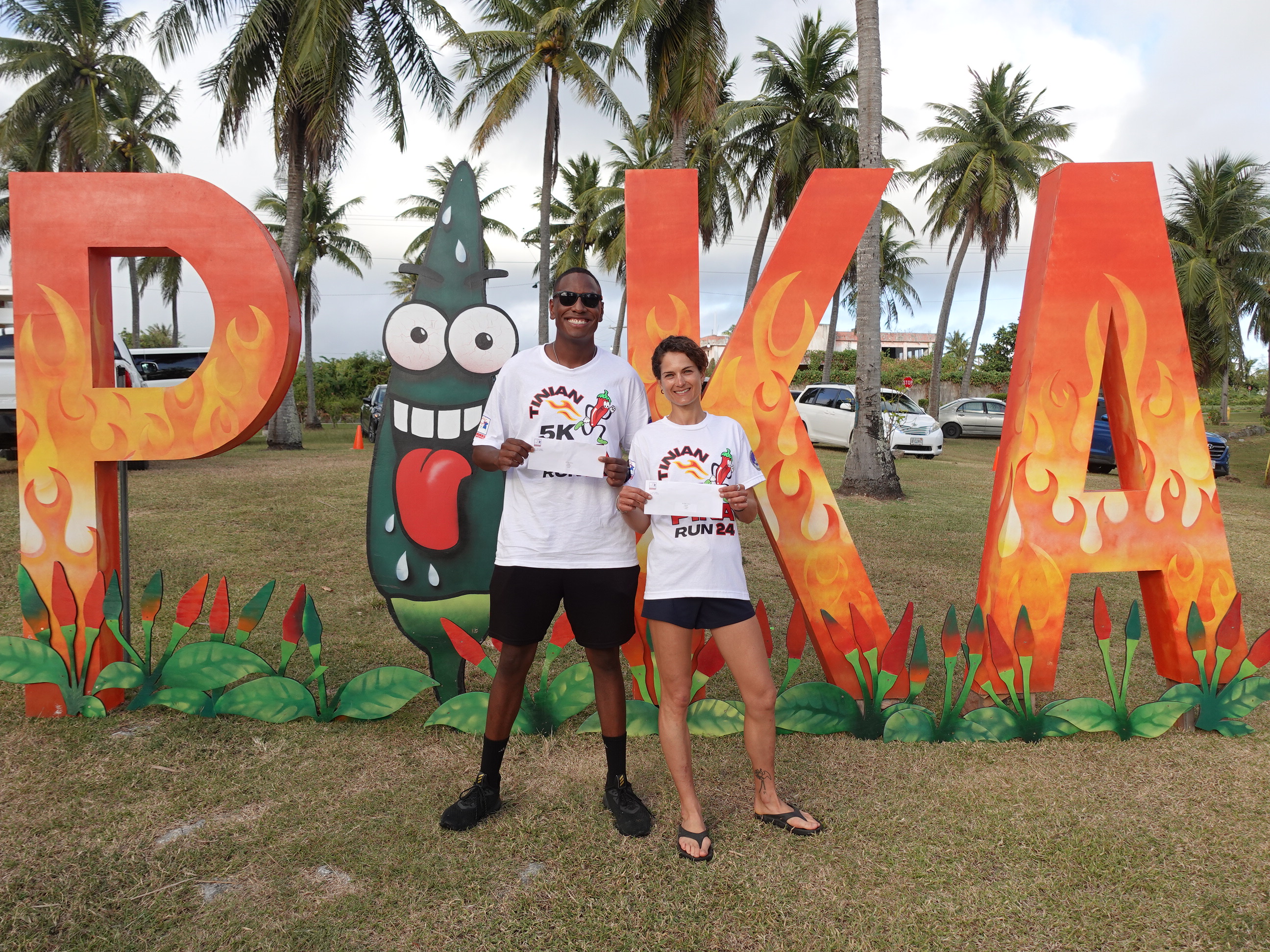 Men’s 2nd place finisher Jeff Pierrot, left, and women’s 1st place finisher Virginie Ternisien accept their prize money for Top 3 finishes in the Pika Fun Run on Feb. 17, 2024, during the 20th Annual Tinian Hot Pepper Festival.  Fifty-eight participants joined the inaugural race at the festival, organized by the Marianas Visitors Authority every President’s Day weekend in February.