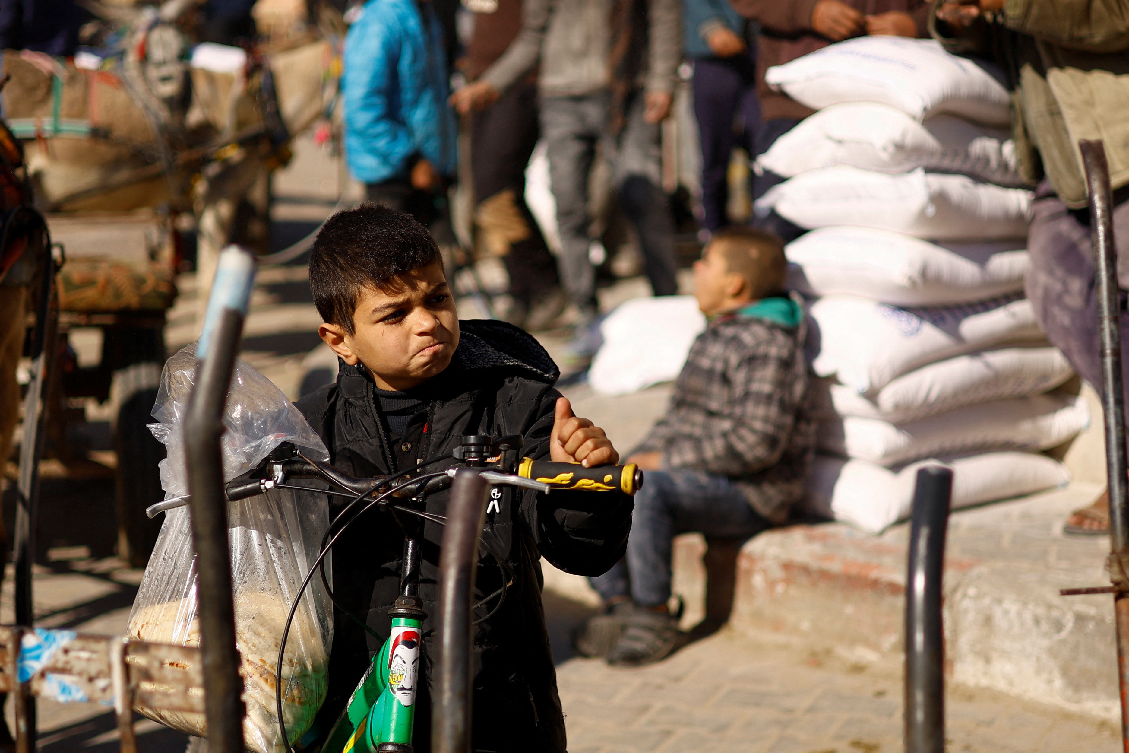 A youth gestures as Palestinians gather to receive bags of flour distributed by the United Nations Relief and Works Agency (UNRWA), amid the ongoing conflict between Israel and Palestinian Islamist group Hamas, in Rafah in the southern Gaza Strip February 1, 2024. 