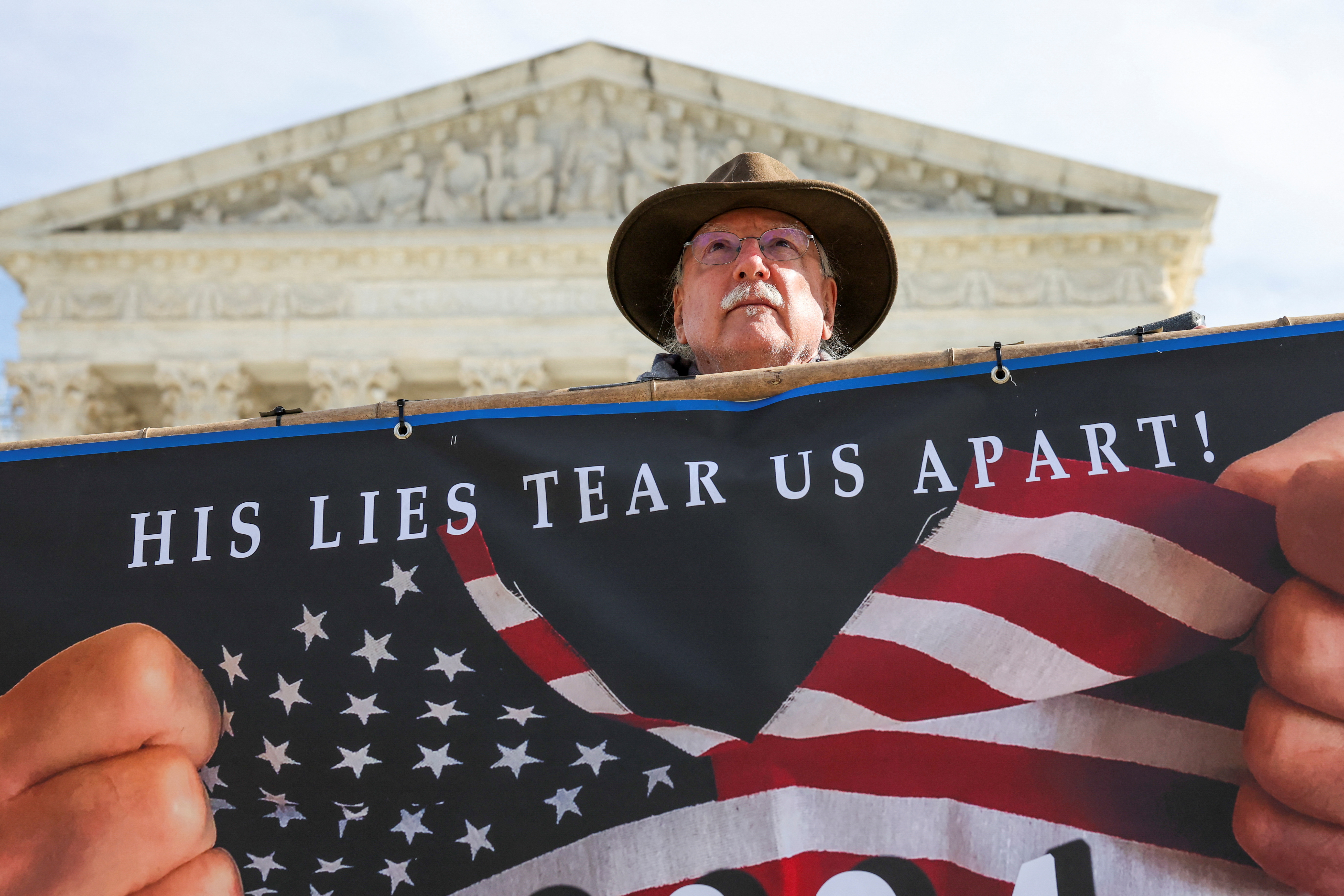 Stephen Parlato of Boulder, Colorado, holds up a sign outside the U.S. Supreme Court as justices hear arguments in former U.S. President Donald Trump's appeal of a lower court's ruling disqualifying him from the Colorado presidential primary ballot, in Washington, U.S., February 8, 2024. 
