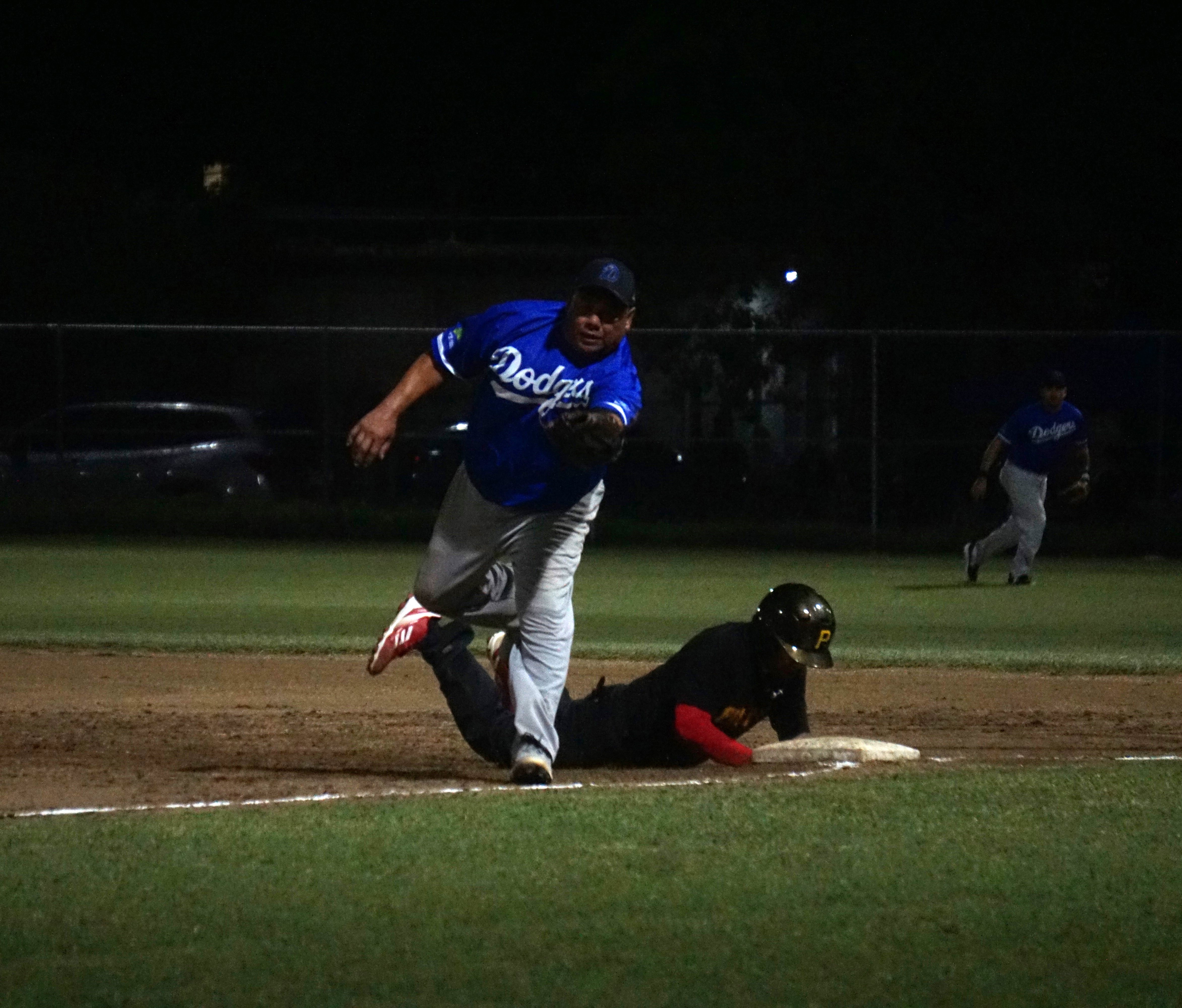 The Pirates' James Fleming slides back to first base safely following a pick-off attempt by the Dodgers’ first baseman, John Acosta, during game 1 of the SBL Masters League championship series at the Francisco “Tan Ko” Palacios Baseball Field on Monday.