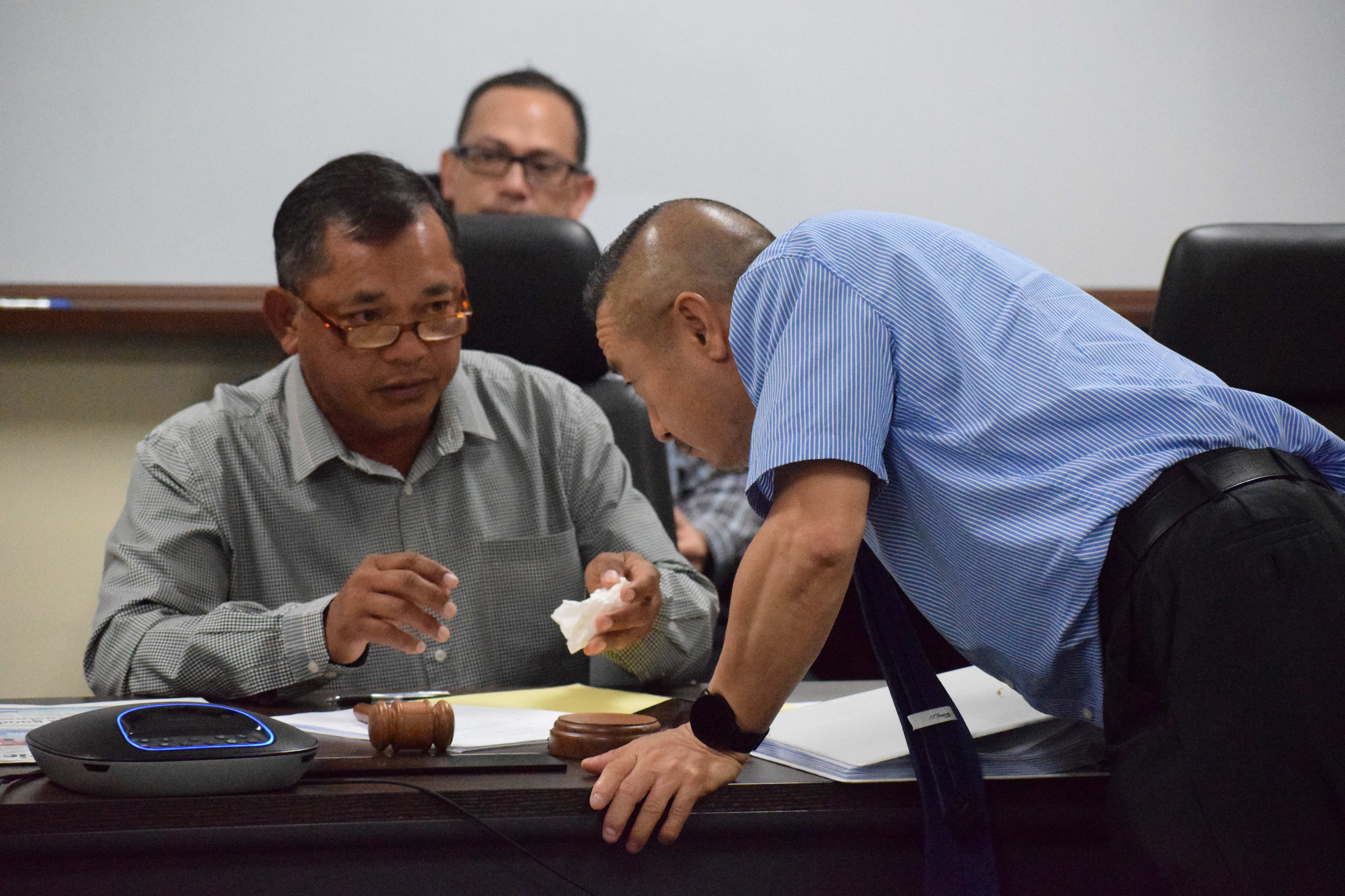 Commonwealth Casino Commission Vice Chair Ralph S. Demapan confers with Executive Director Andrew Yeom as Assistant Attorney General Carl Dela Cruz looks on during a revocation hearing in the commission's conference room Wednesday morning.