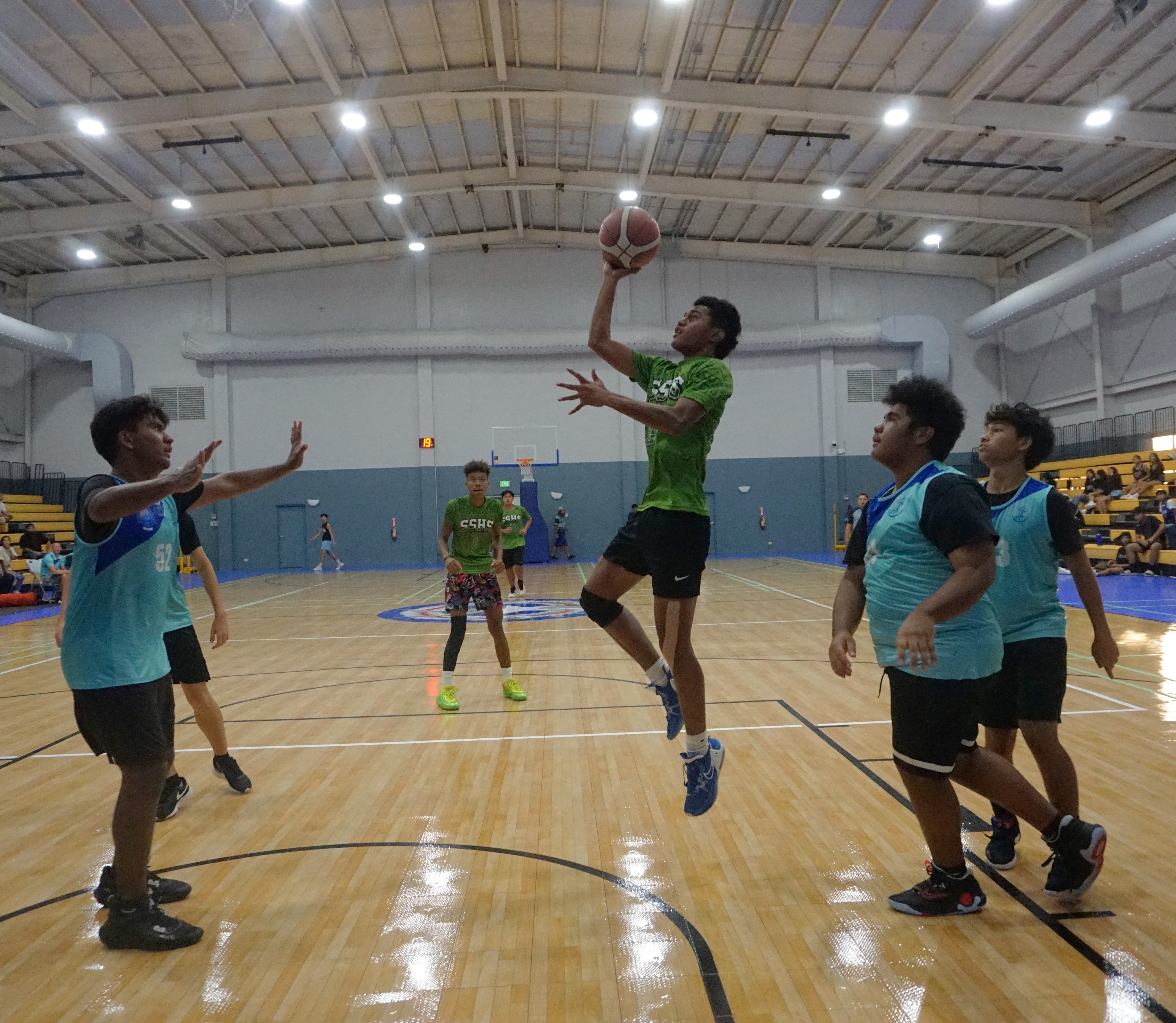 SSHS' Slymark Defang finishes with a floater between SIS defenders during a boys high school division game of the IT&E Interscholastic Basketball League SY23-24 at the Ada gym on Friday.