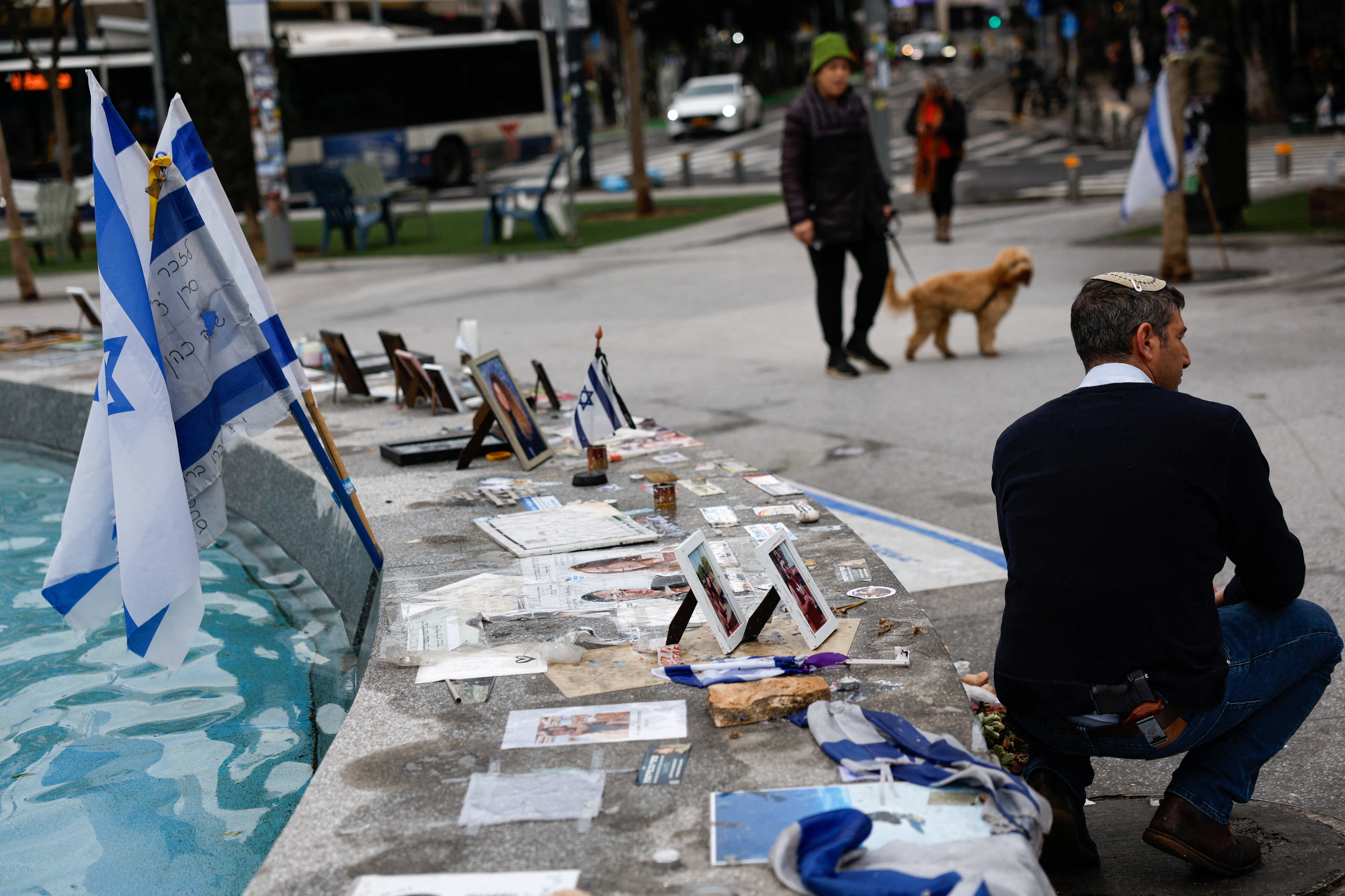 A man with a gun tucked into in his belt poses for a picture next to tributes to the victims of the deadly October 7 attack by Palestinian Islamist group Hamas, at a fountain in Tel Aviv, Israel, February 1, 2024. 