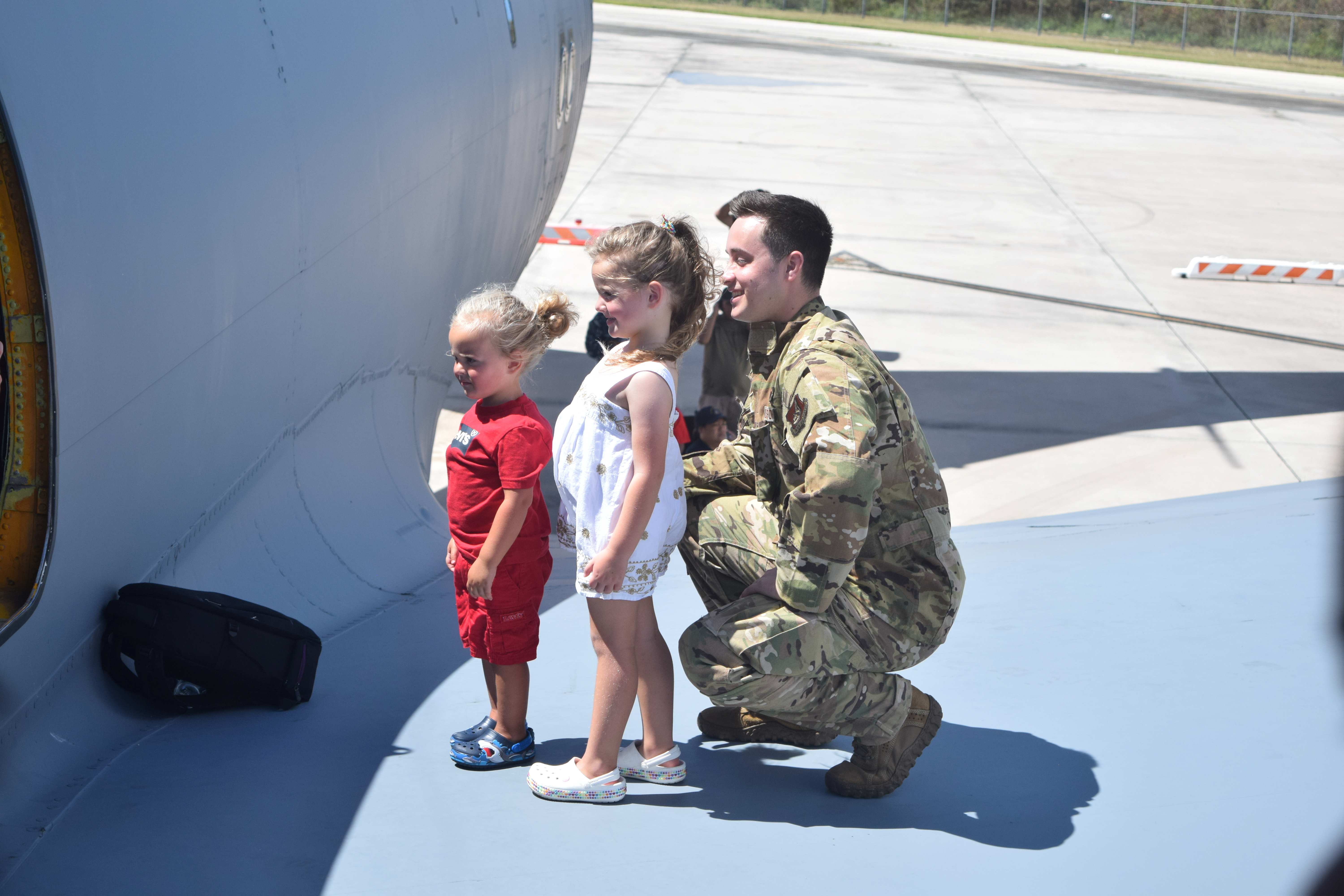Two girls pose with a 909th Air Refueling Squadron officer.