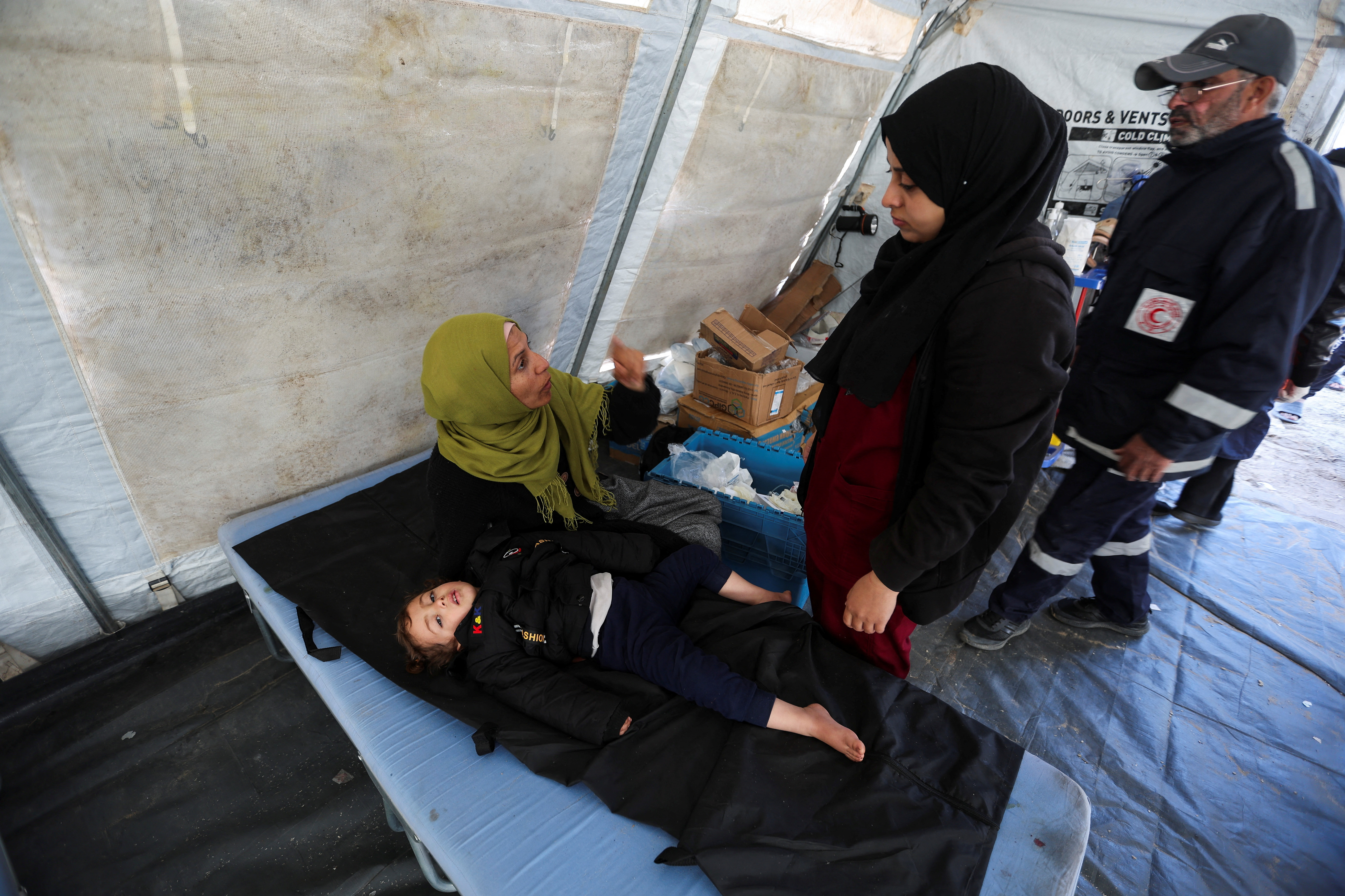 A woman reacts next to a child as medics help Palestinians at a medical point, formed to get better access to frontlines, amid the ongoing conflict between Israel and Hamas, in Khan Younis in the southern Gaza Strip January 30, 2024.