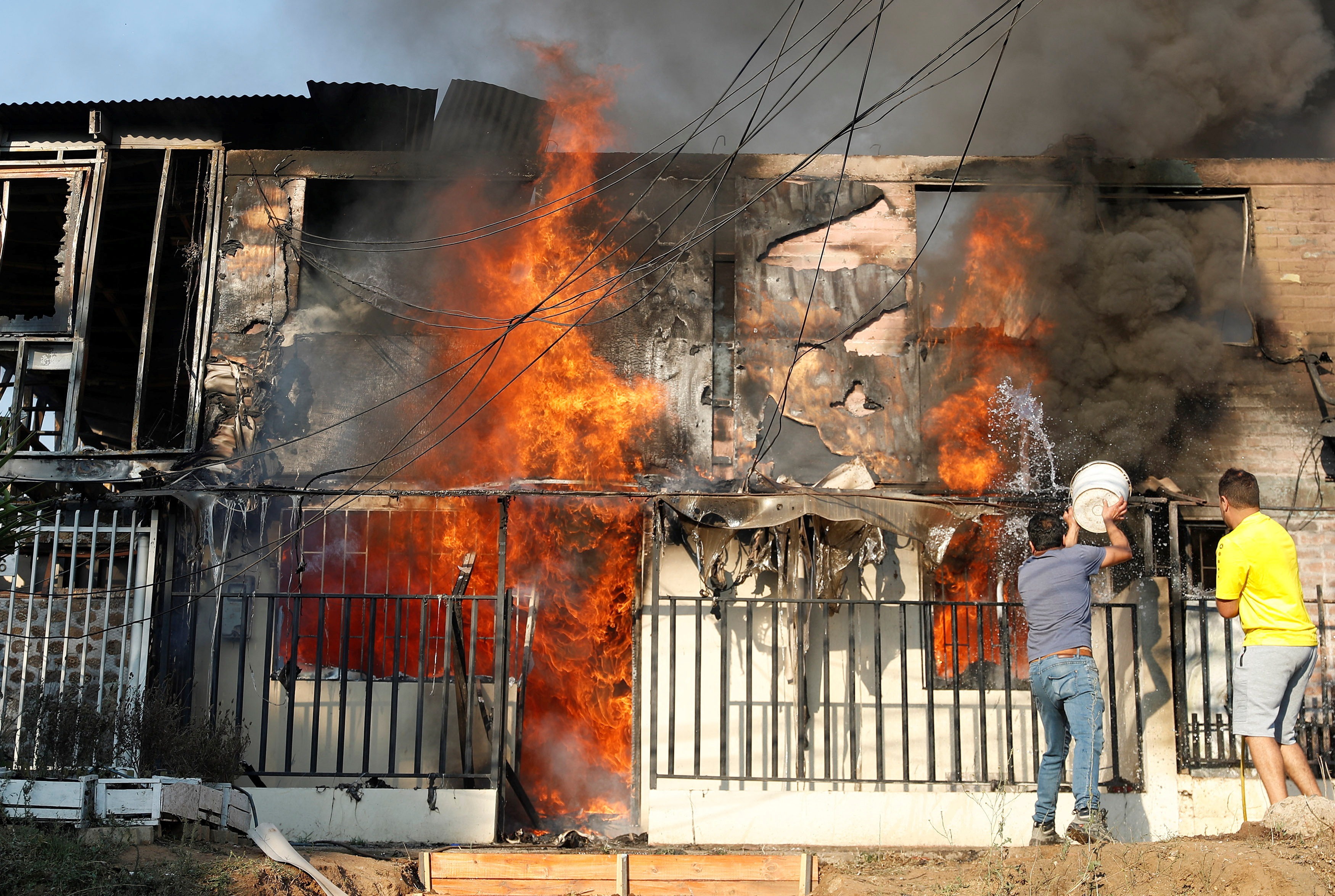 People try to extinguish a fire burning a house during the spread of wildfires in Vina del Mar, Chile February 3, 2024. 