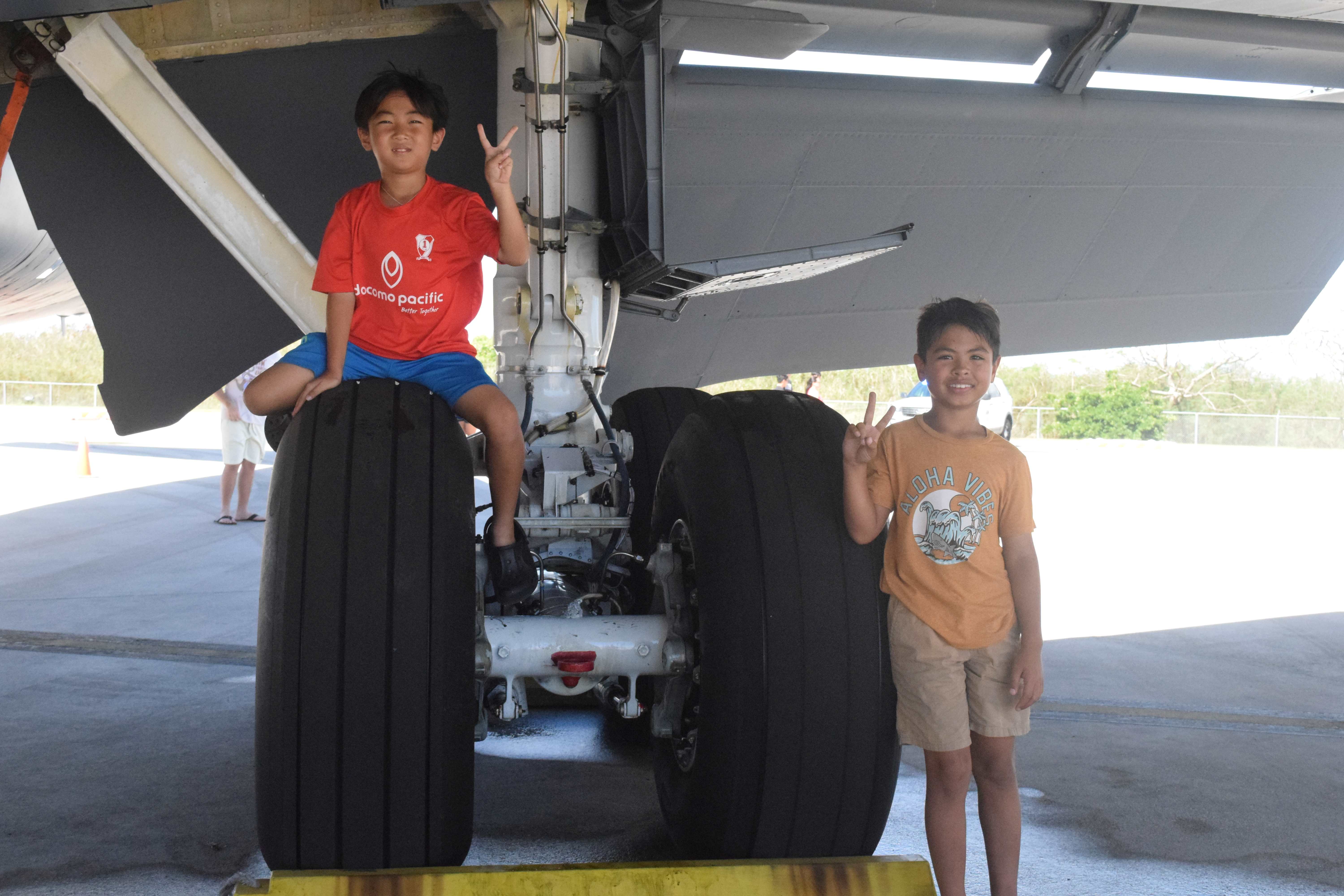 Two boys pose for a photo near two of the tires of the U.S. Air Force 909th Air Refueling Squadron's KC-135 Air-to-Air refueling aircraft.