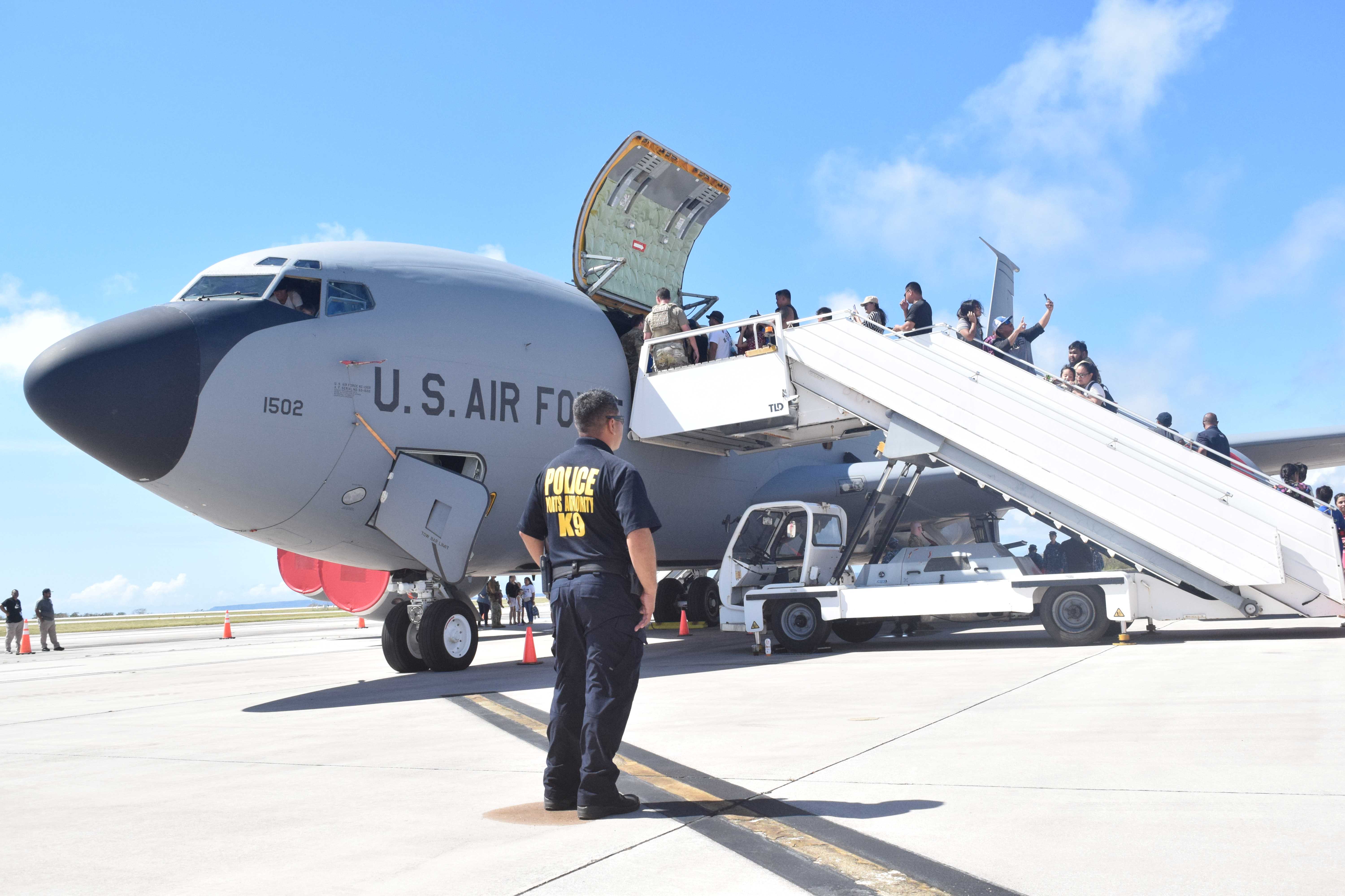 A Commonwealth Ports Authority Airport police officer looks on as members of the community line up for the “Pet a Jet” experience.