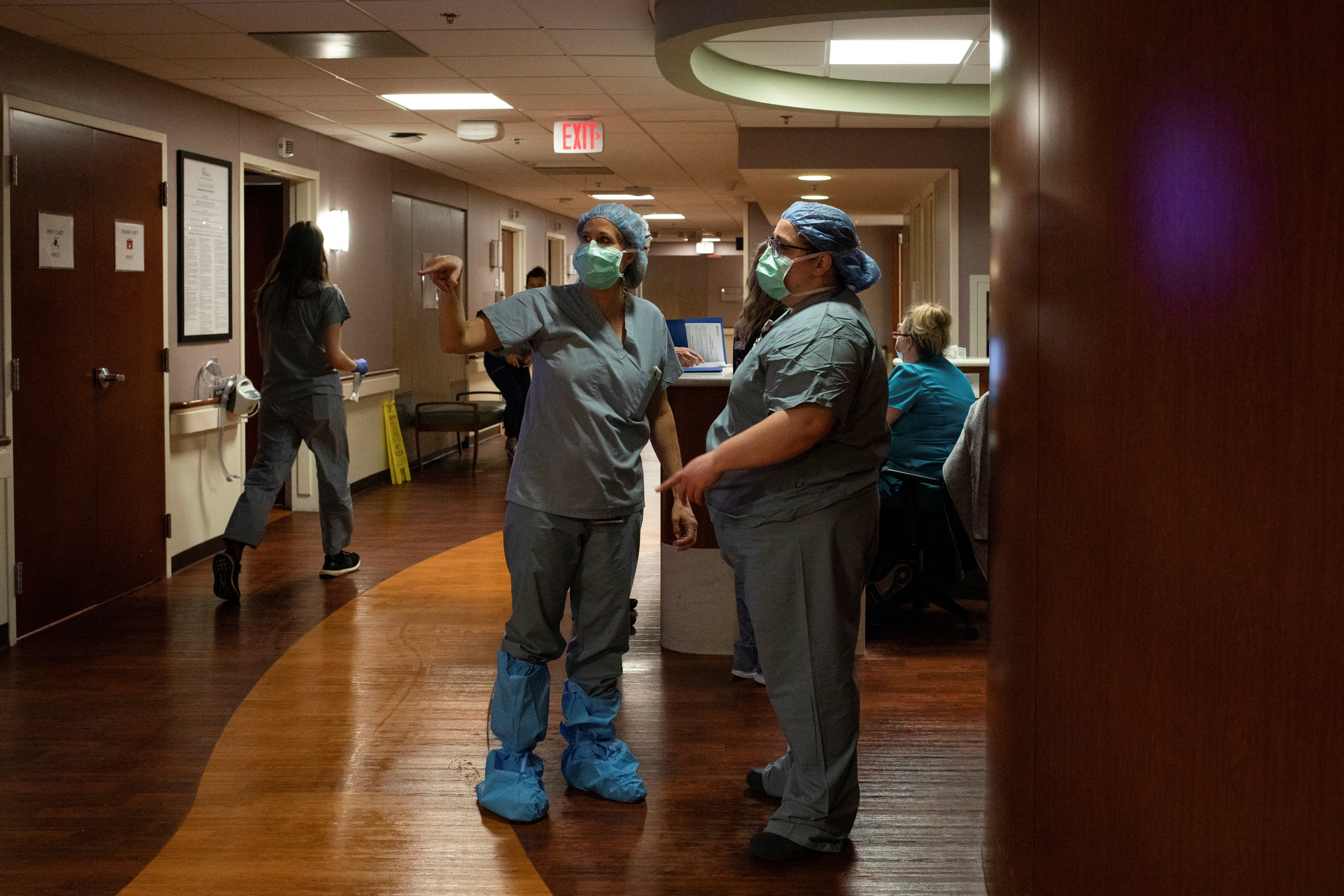 A doctor and nurse consult in the hallway as a patient prepares to be transferred for an emergency C-section in the Family Birth Center at Beaumont Hospital in Royal Oak, Michigan, U.S., February 1, 2022. 