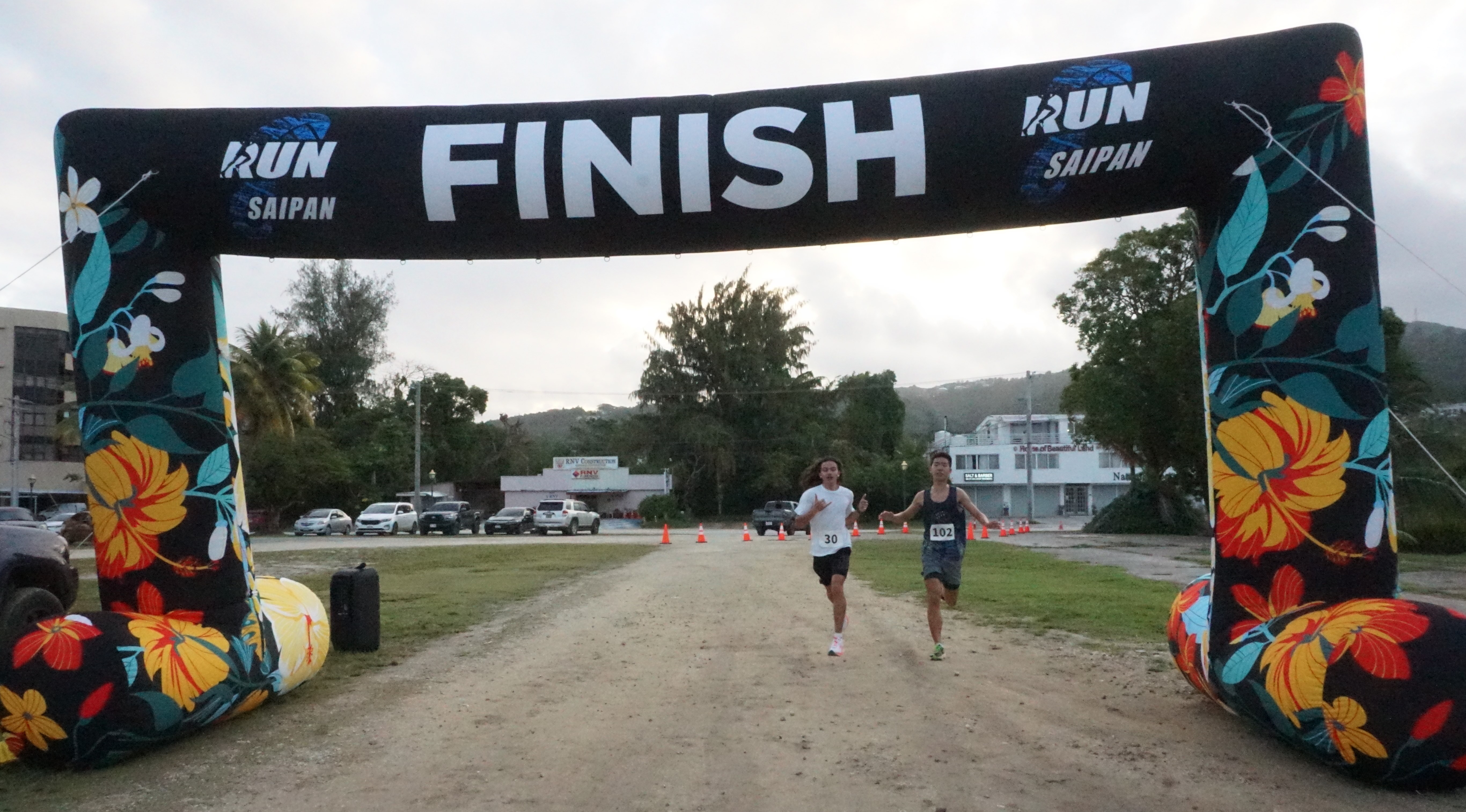 Rex Pixley and Pony Tang cross the finish line together during the Rotaract Club of Saipan 5K Fun Run at the Garapan Fishing Base on Saturday.