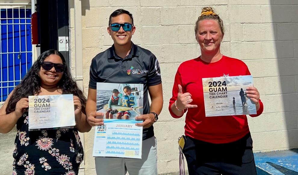 Gabriella Topasña, left, and Phillip Cruz, center, with the University of Guam Center for Island Sustainability share the 2024 Guam Tide Chart Calendar with an employee at Axe Murderer Tours in Hagåtña. 