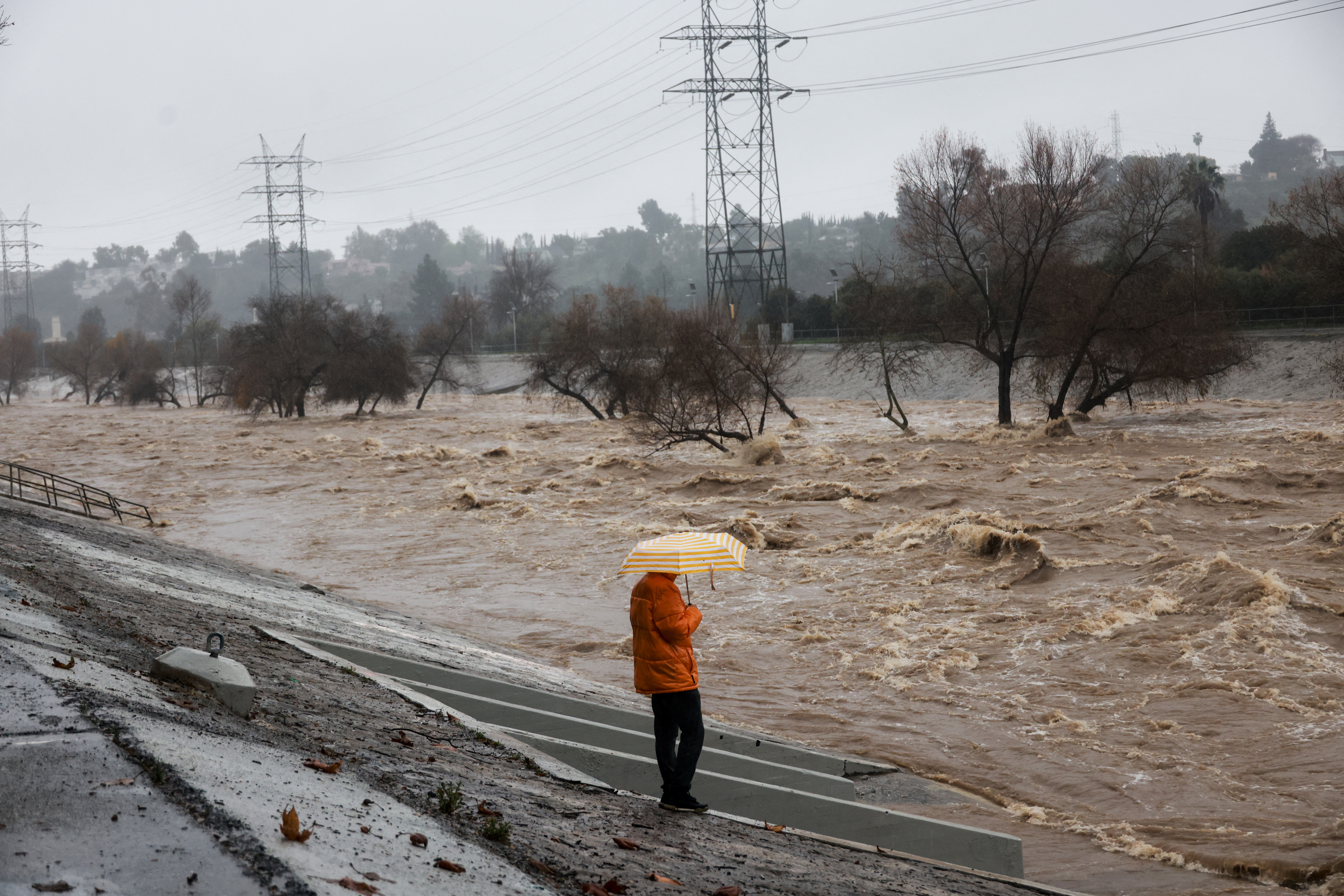 A person holding an umbrella watches the Los Angeles river during heavy rains in Los Angeles, California, U.S., February 5, 2024.