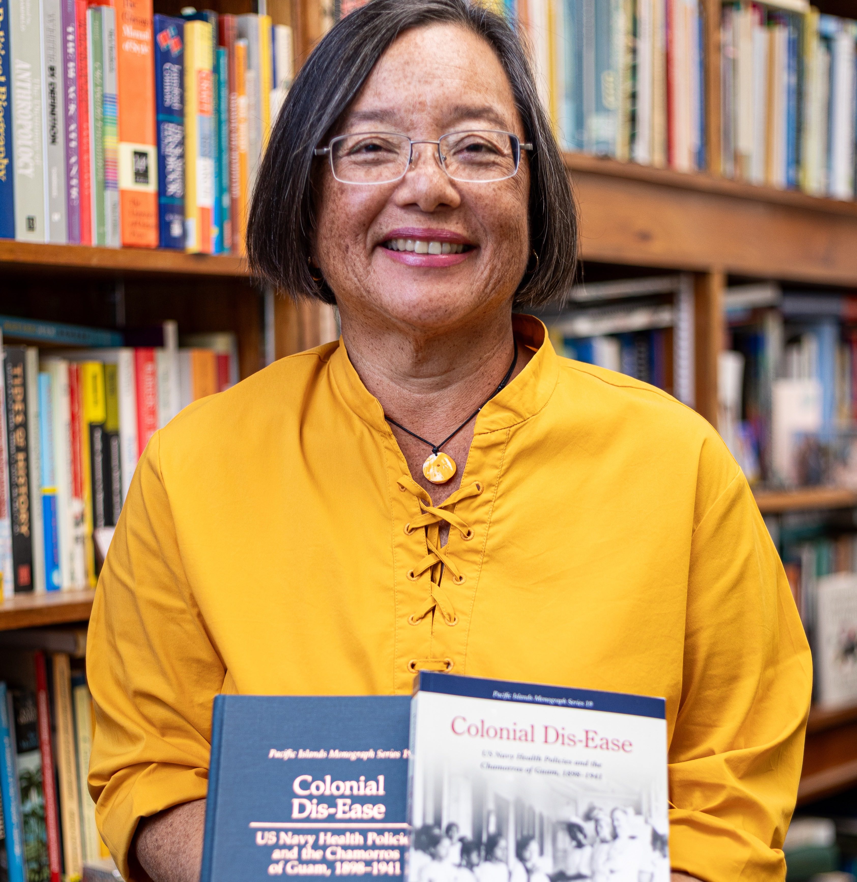 Dr. Anne Perez Hattori, professor of History, CHamoru Studies, and Micronesian Studies at the University of Guam, holds the first and reprinted editions of her book “Colonial Dis-Ease: US Navy Health Policies and the Chamorros of Guam, 1898–1941.”