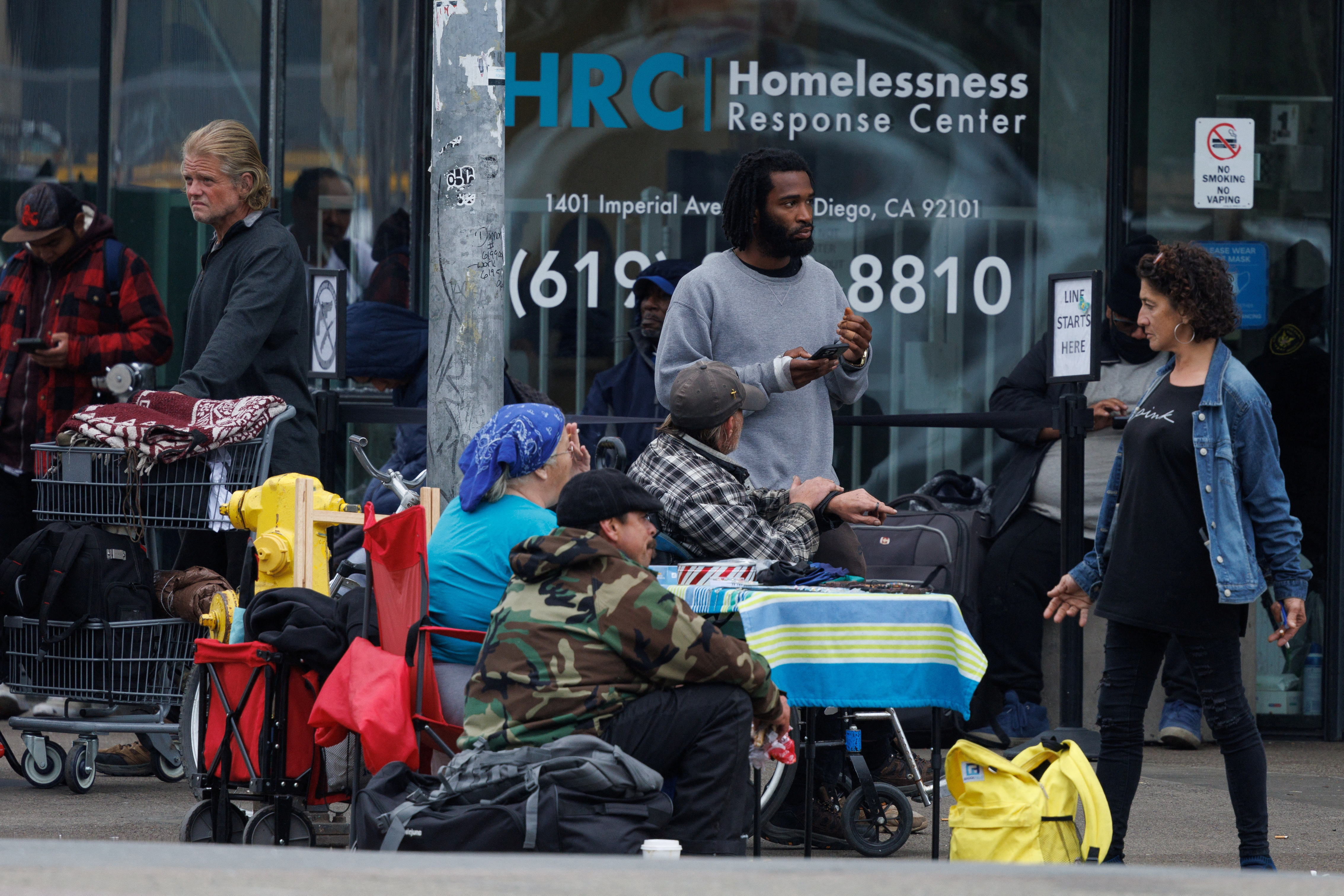 Homeless people wait on a sidewalk outside a homeless response center in downtown San Diego, California, U.S., February 26, 2024. 