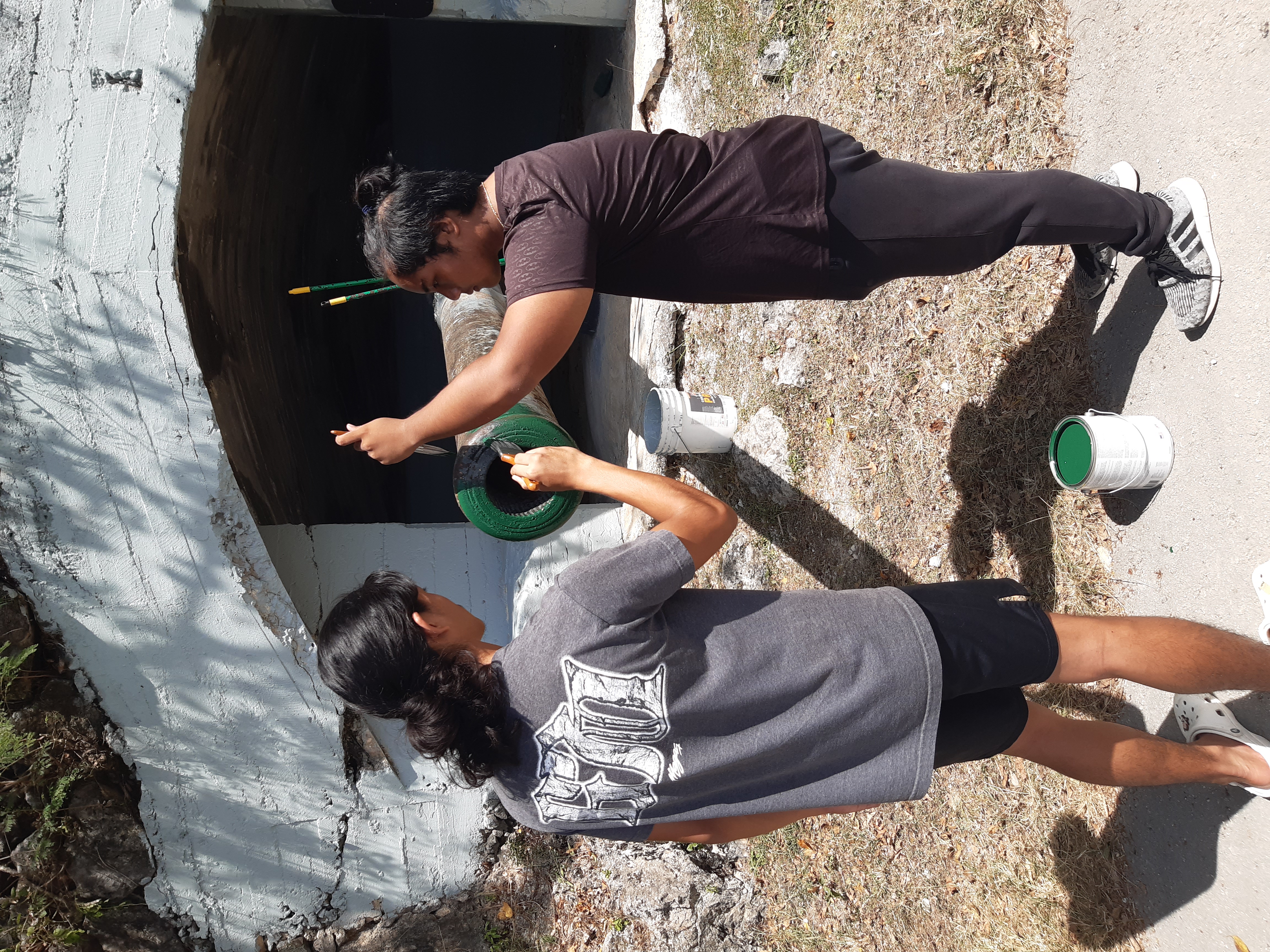 J.D. Barcinas, left, and Sonjoe Manuel of Dr. Rita S. Inos Jr./Sr. High in Rota repaint a historic Japanese cannon in February 2024.  The students are working with the Marianas Visitors Authority under the CNMI Public School System Co-op Education Program.