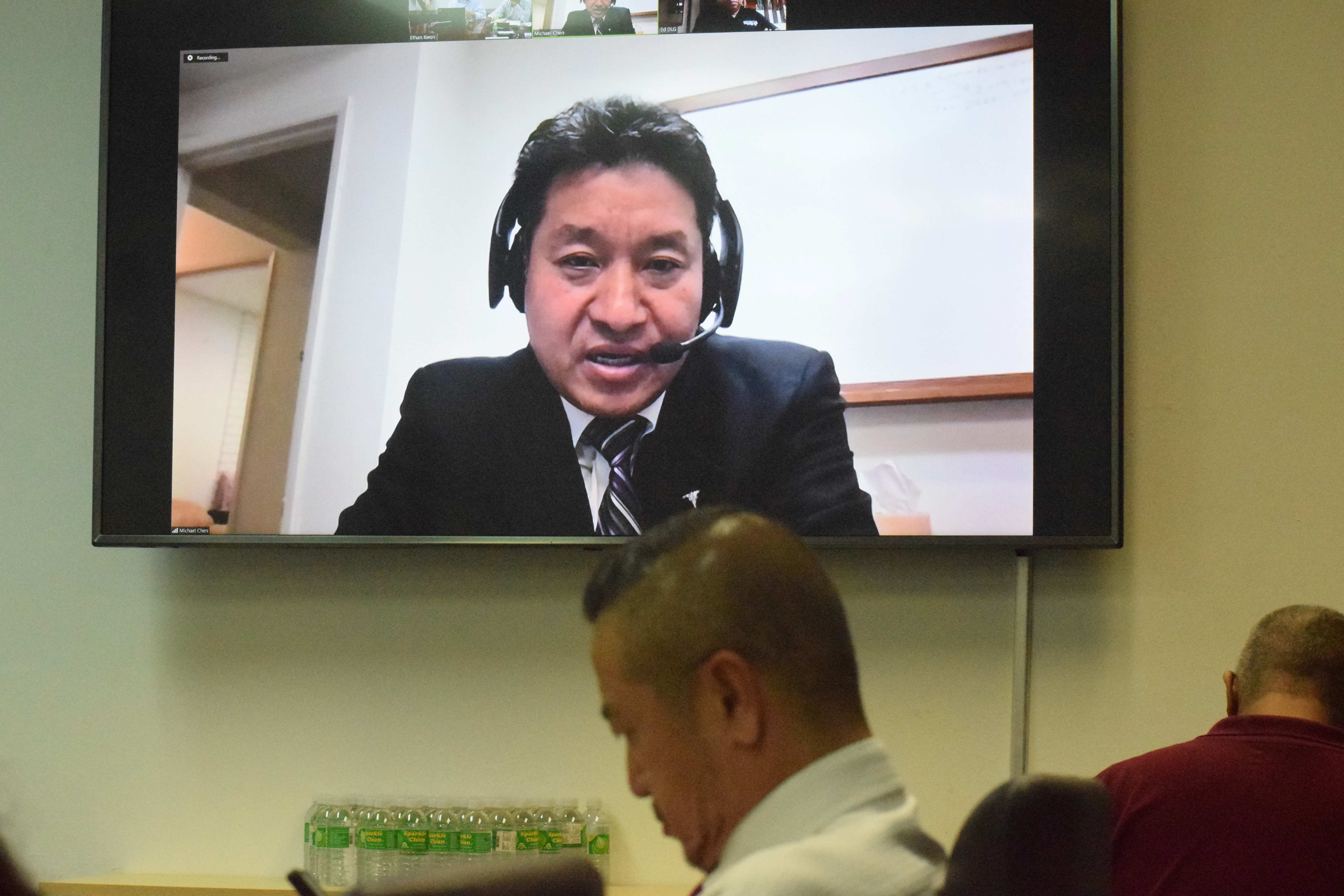 Imperial Pacific International legal counsel Michael Chen speaks via Zoom as Commonwealth Casino Commission Executive Director Andrew Yeom listens during a revocation hearing conducted by CCC in the governor's conference room on Capital Hill, Thursday.