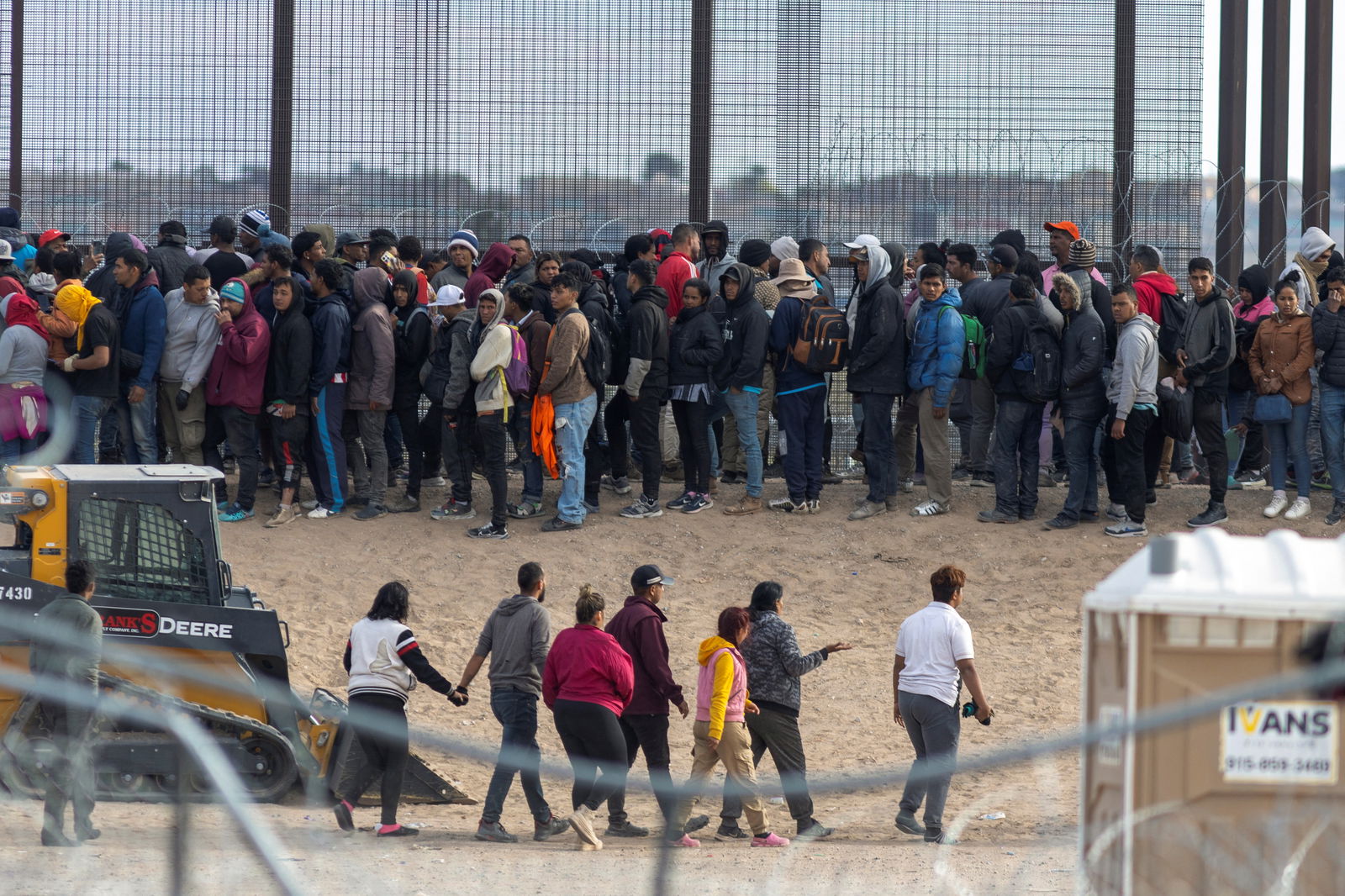 Migrants queue next to the border wall after forcing their way into the U.S. by breaking through razor wire and a fence, as SB 4 law that would empower law enforcement authorities in the state to arrest people suspected of illegally crossing the U.S.-Mexico border was temporarily blocked, as seen from Ciudad Juarez, Mexico, March 21, 2024. 