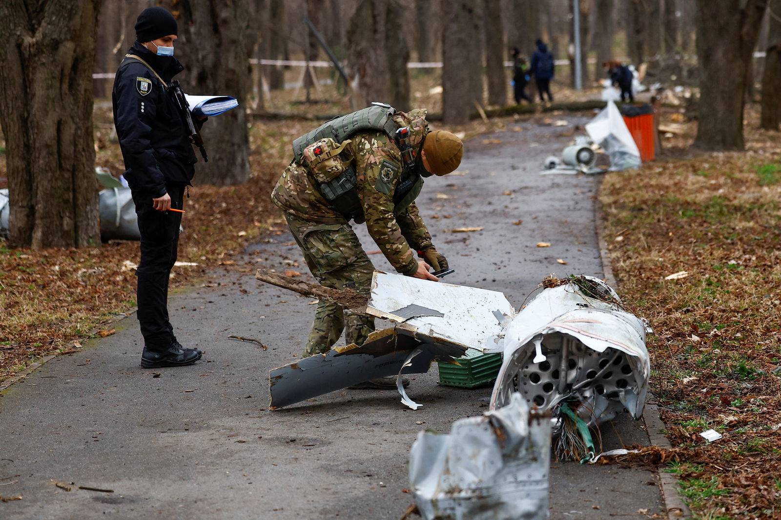 Police officers inspect a part of a Russian Kh-55 cruise missile in a park in Kyiv, March 24, 2024. 