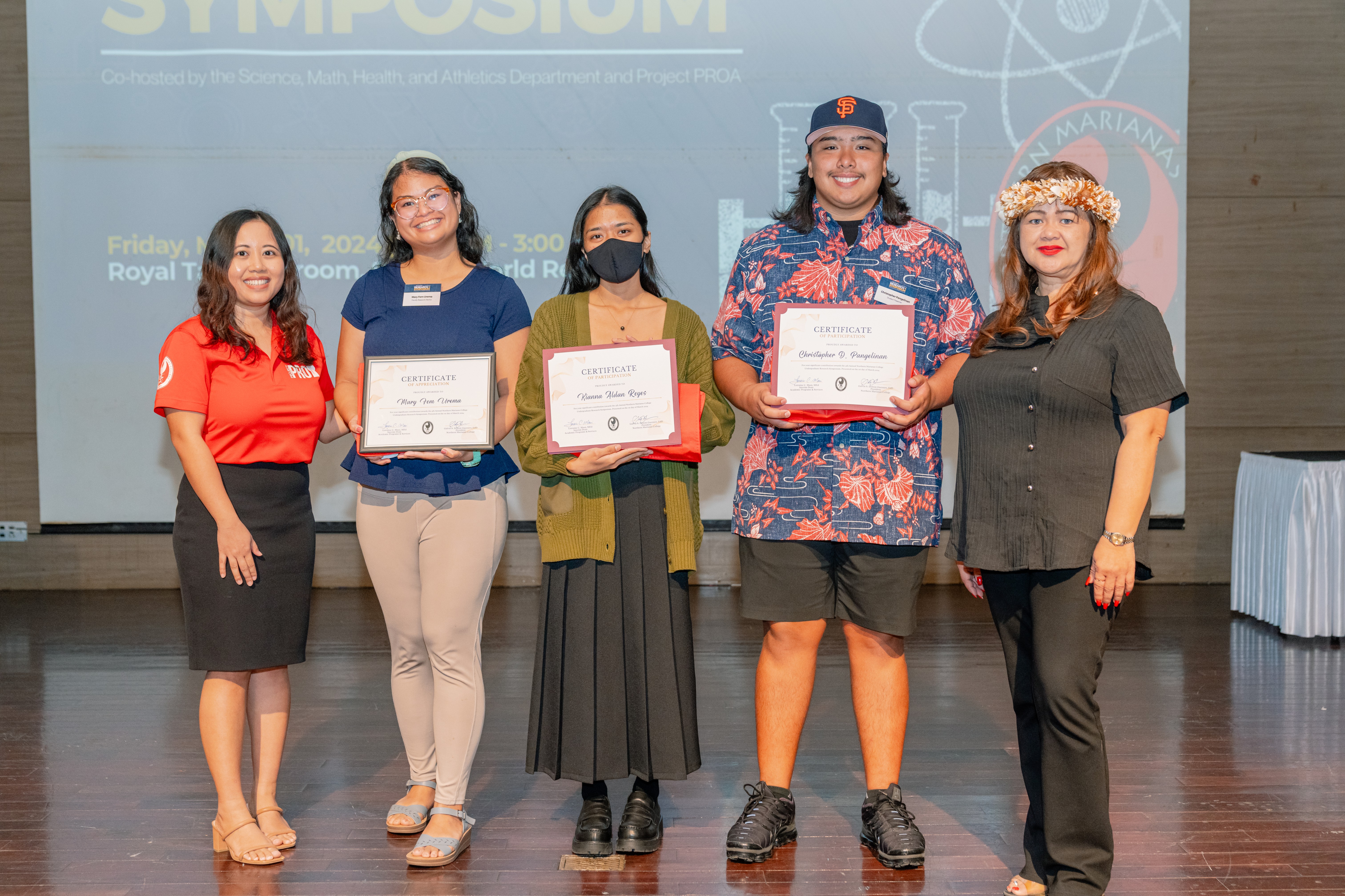 Kianna Reyes and Christopher Pangelinan are each given a certificate of participation for sharing their research at the symposium. Mary Fem Urema served as their research mentor.