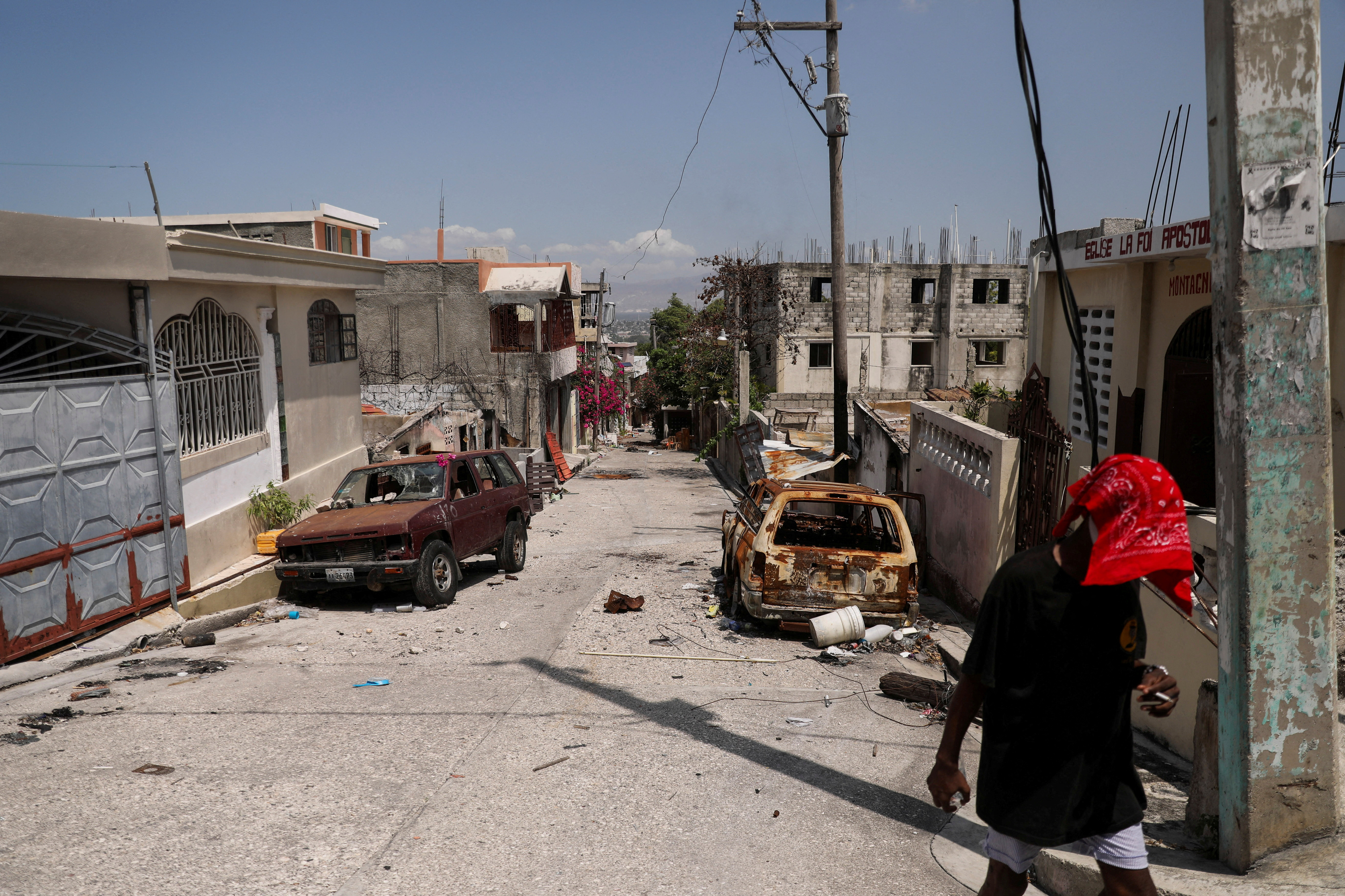A person walks past damaged cars in the Carrefour Feuilles neighborhood, which was deserted due to gang violence, in Port-au-Prince, Haiti March 19, 2024. 