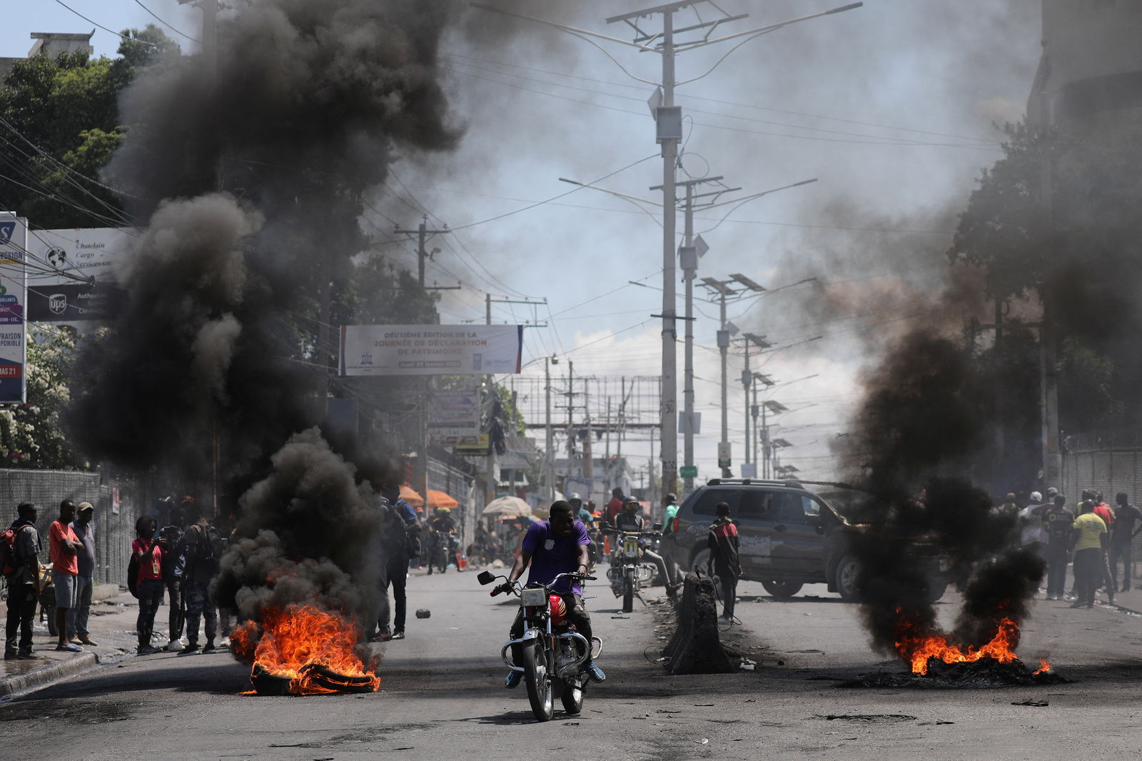 Motorists pass by a burning barricade during a protest as the government said it would extend a state of emergency for another month after an escalation in violence from gangs seeking to oust the Prime Minister Ariel Henry, in Port-au-Prince, Haiti, March 7, 2024.