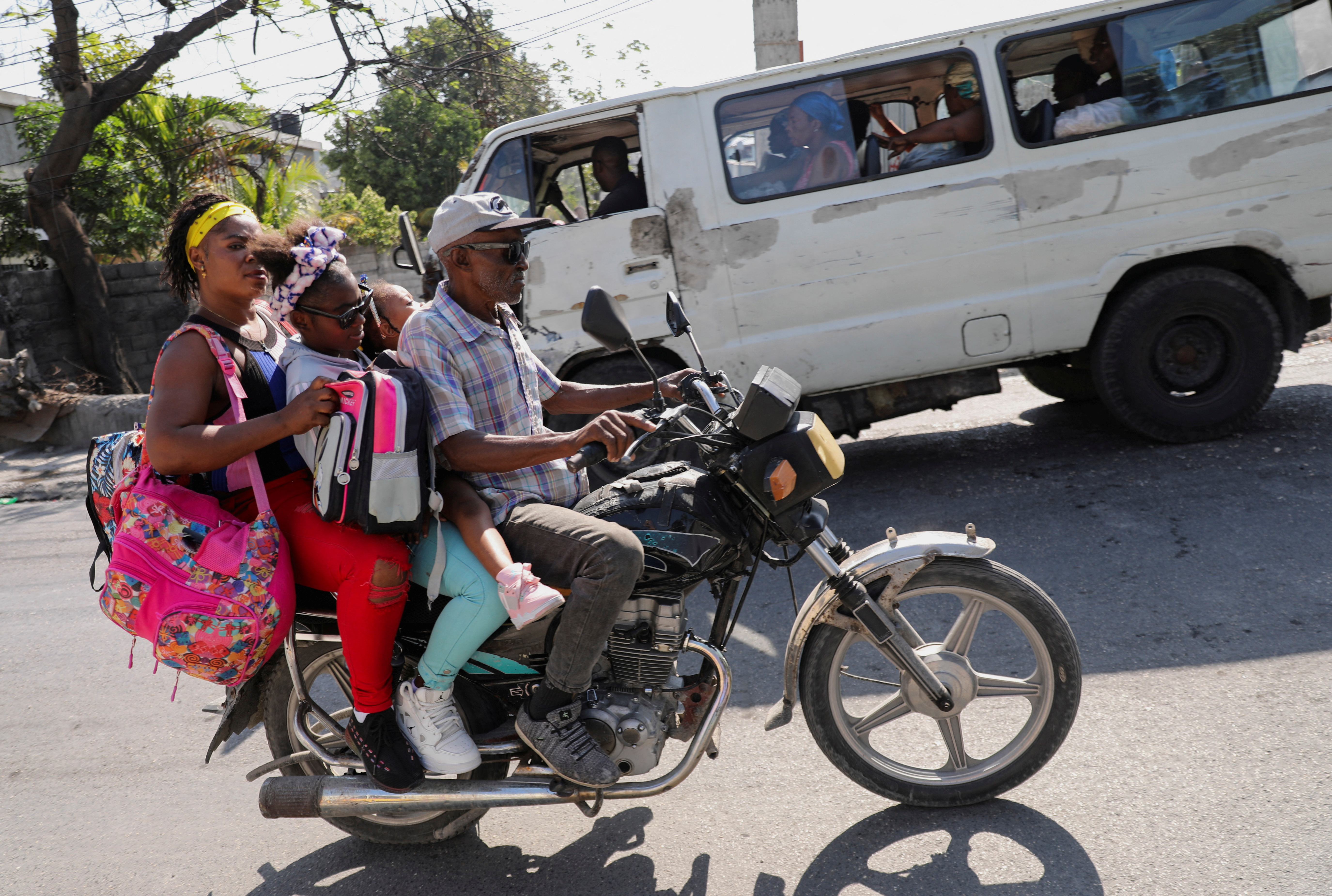 A man rides a motorbike carrying people and their belongings along a street after Haiti's Prime Minister Ariel Henry pledged to step down following months of escalating gang violence, in Port-au-Prince, Haiti March 12, 2024. 
